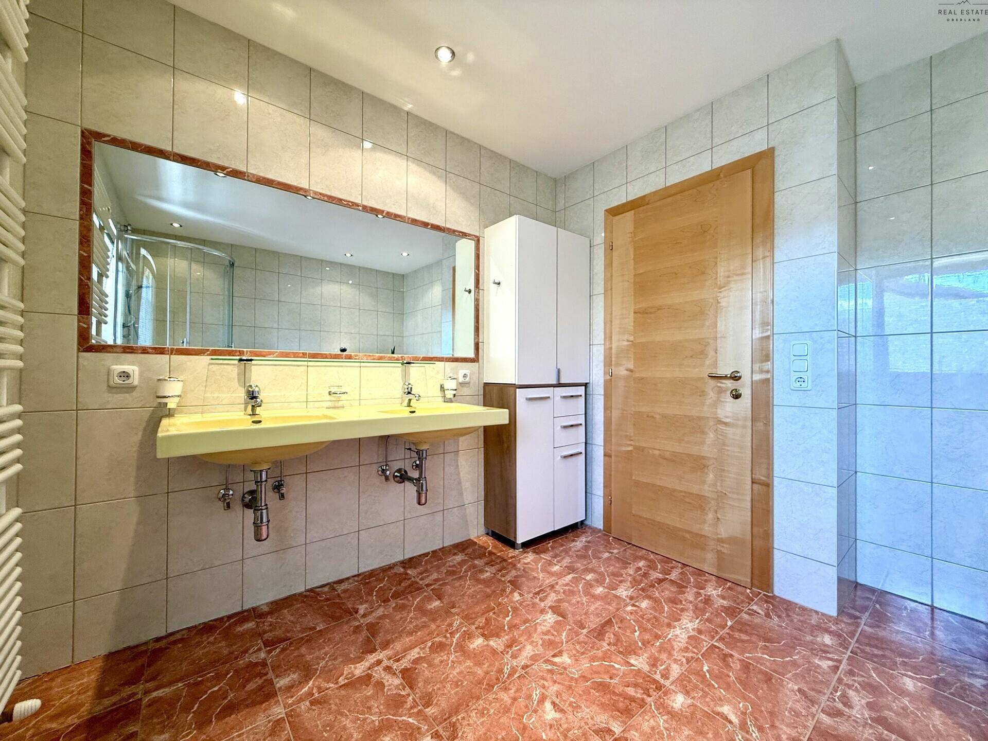 Badezimmer mit Doppelwaschbecken, großem Spiegel und Handtuchheizkörper, hell und funktional gestaltet.