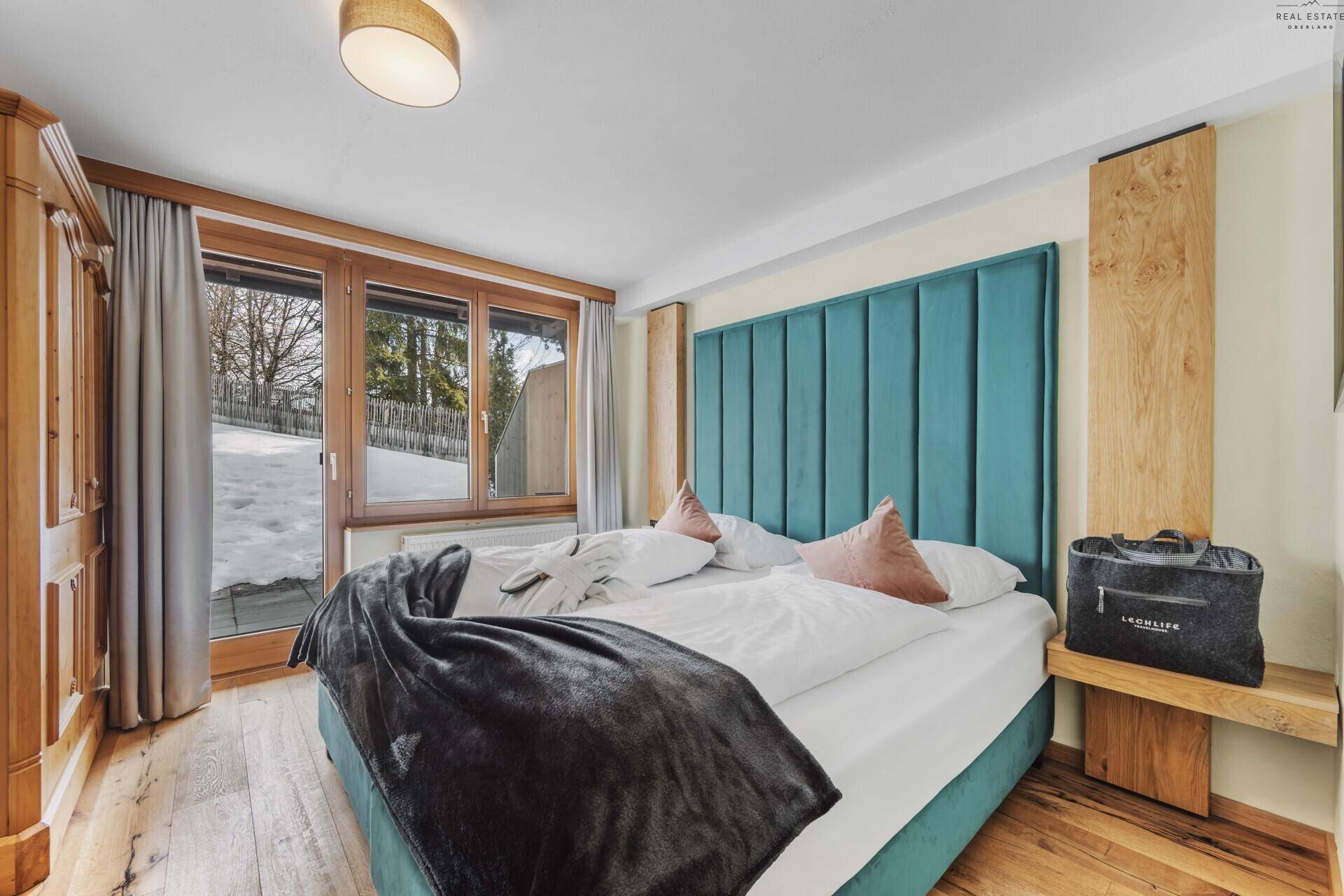 Gemütliches Schlafzimmer mit Doppelbett, Holzschrank und Zugang zum Balkon.