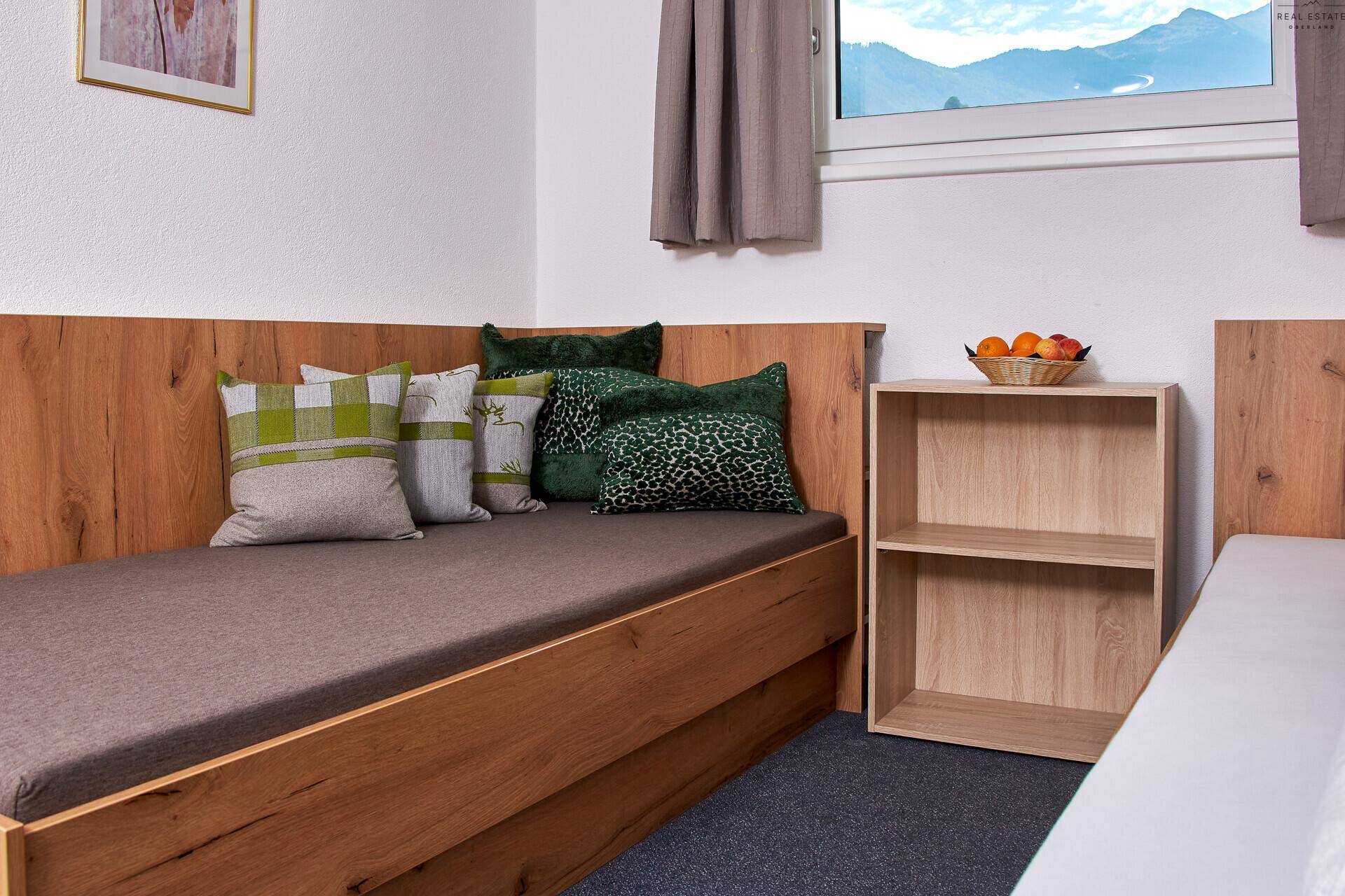 Gemütliches Schlafzimmer mit zwei Einzelbetten, Holzbettrahmen und grünen Kissen.