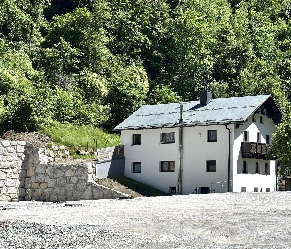 Freistehendes Haus mit Balkon und Steinfassade im alpinen Stil.