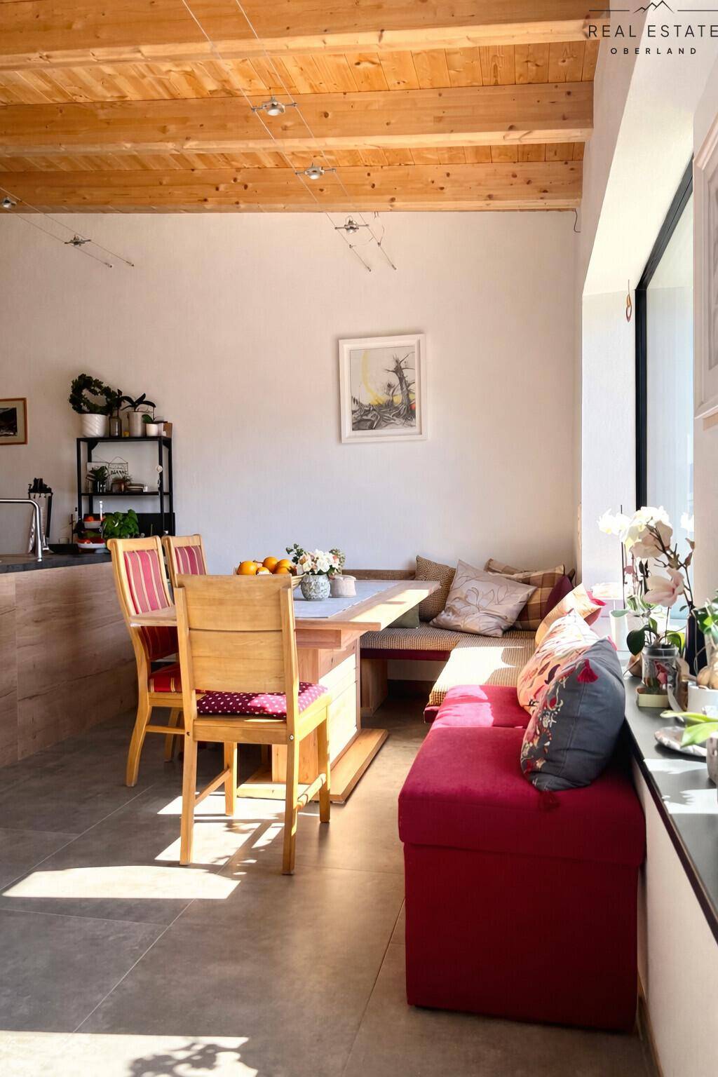 Heller Essbereich mit Holztisch, Sitzbank und rotem Sofa, direkt an der Küche gelegen.