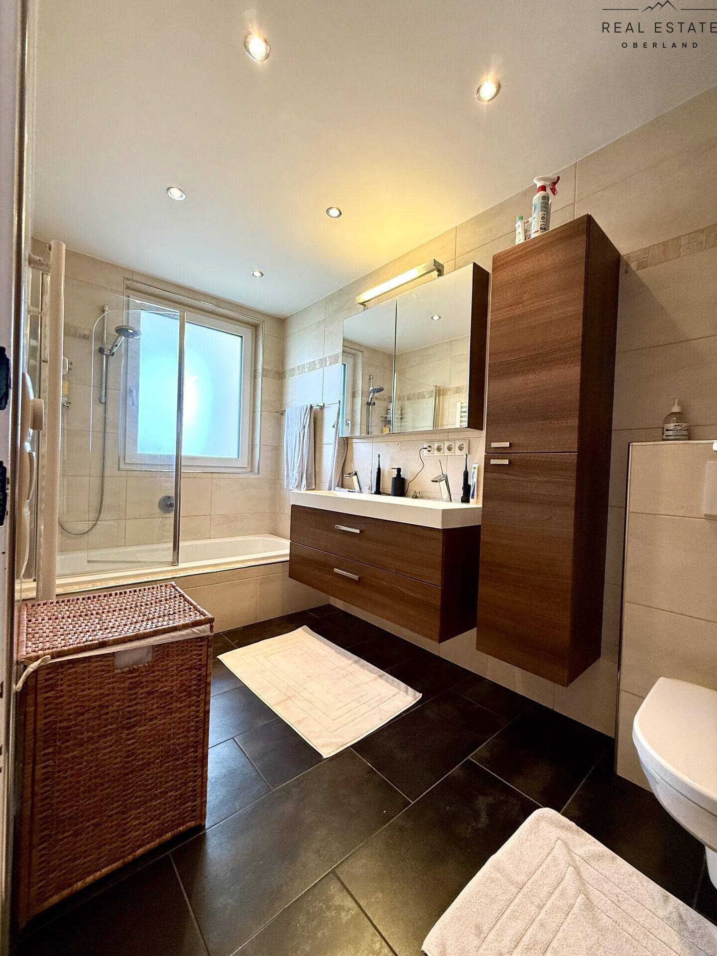 Modernes Badezimmer mit Badewanne, Dusche, Waschbecken und Fenster.