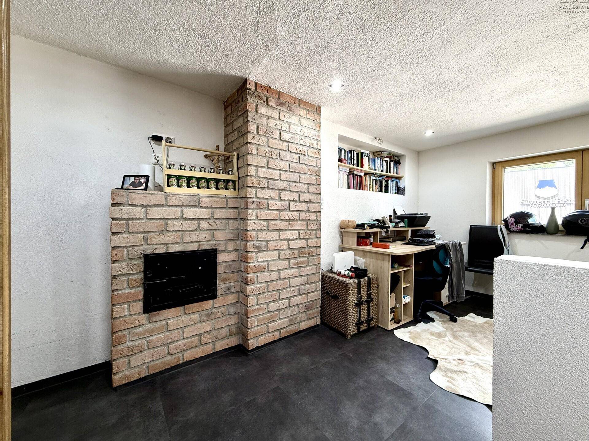 Arbeitszimmer mit Ziegelkamin, Bücherregal und Schreibtisch, bietet eine gemütliche Atmosphäre.