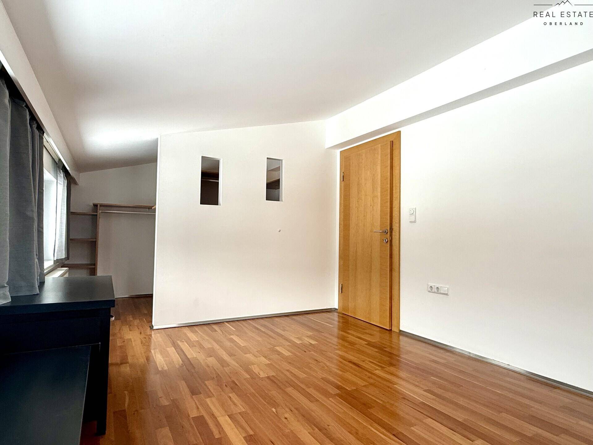 Geräumiges Zimmer mit Holzfußboden, weißen Wänden und Dachschrägen, ideal als Schlaf- oder Arbeitszimmer.