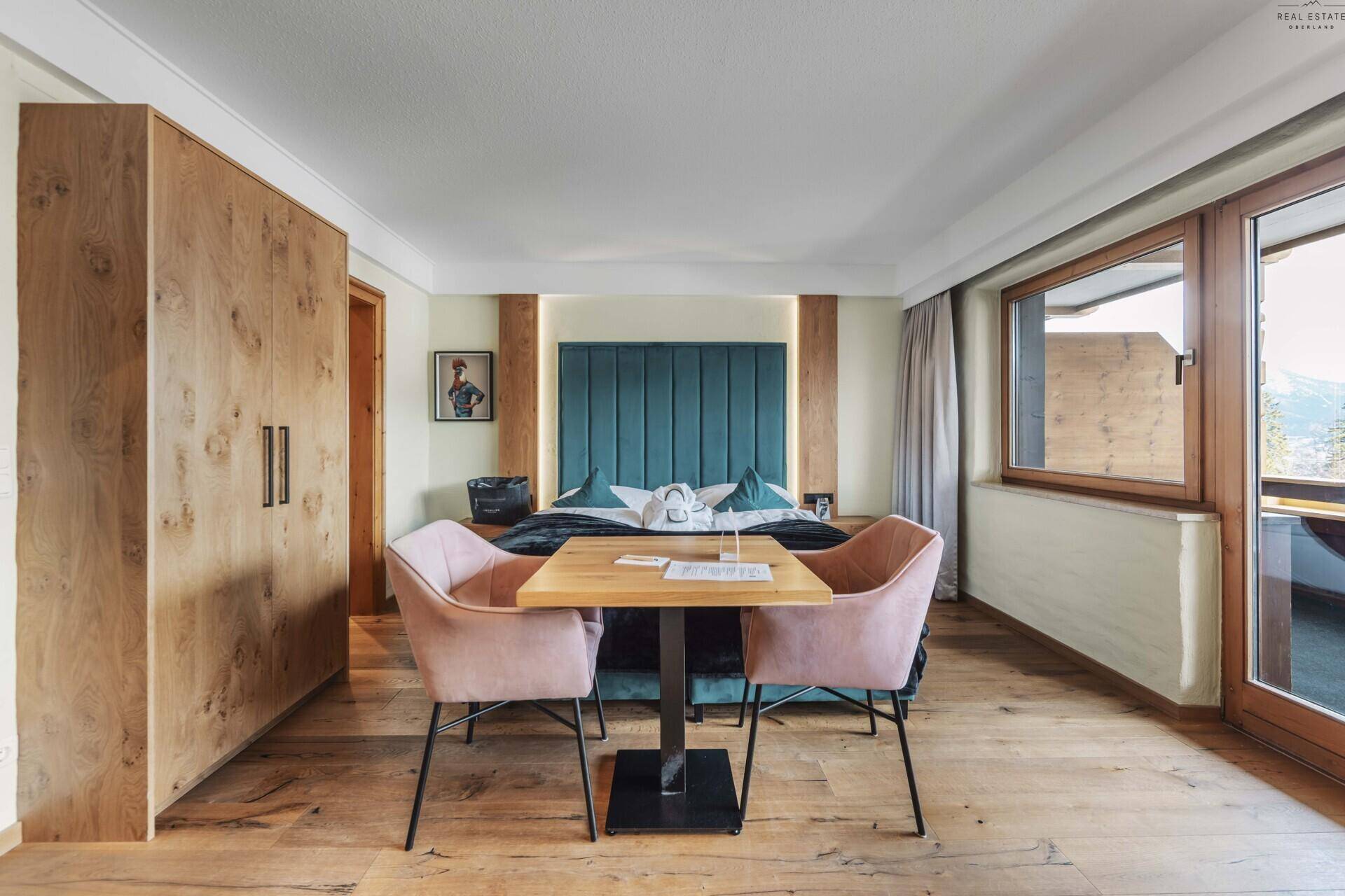 Gemütliches Schlafzimmer mit großem Bett, kleinem Esstisch und eleganten Holzschränken.