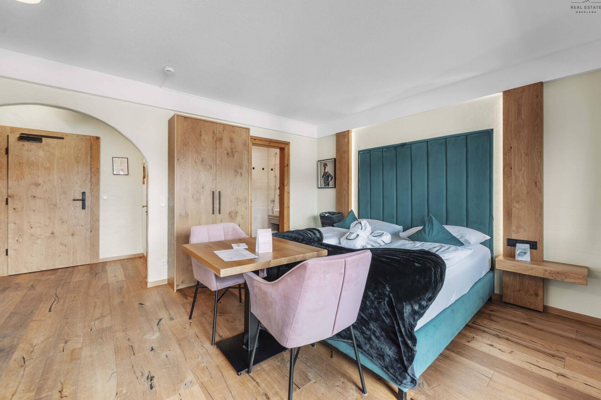 Geräumiges Schlafzimmer mit Holzboden, bequemen Möbeln und Zugang zum Badezimmer.