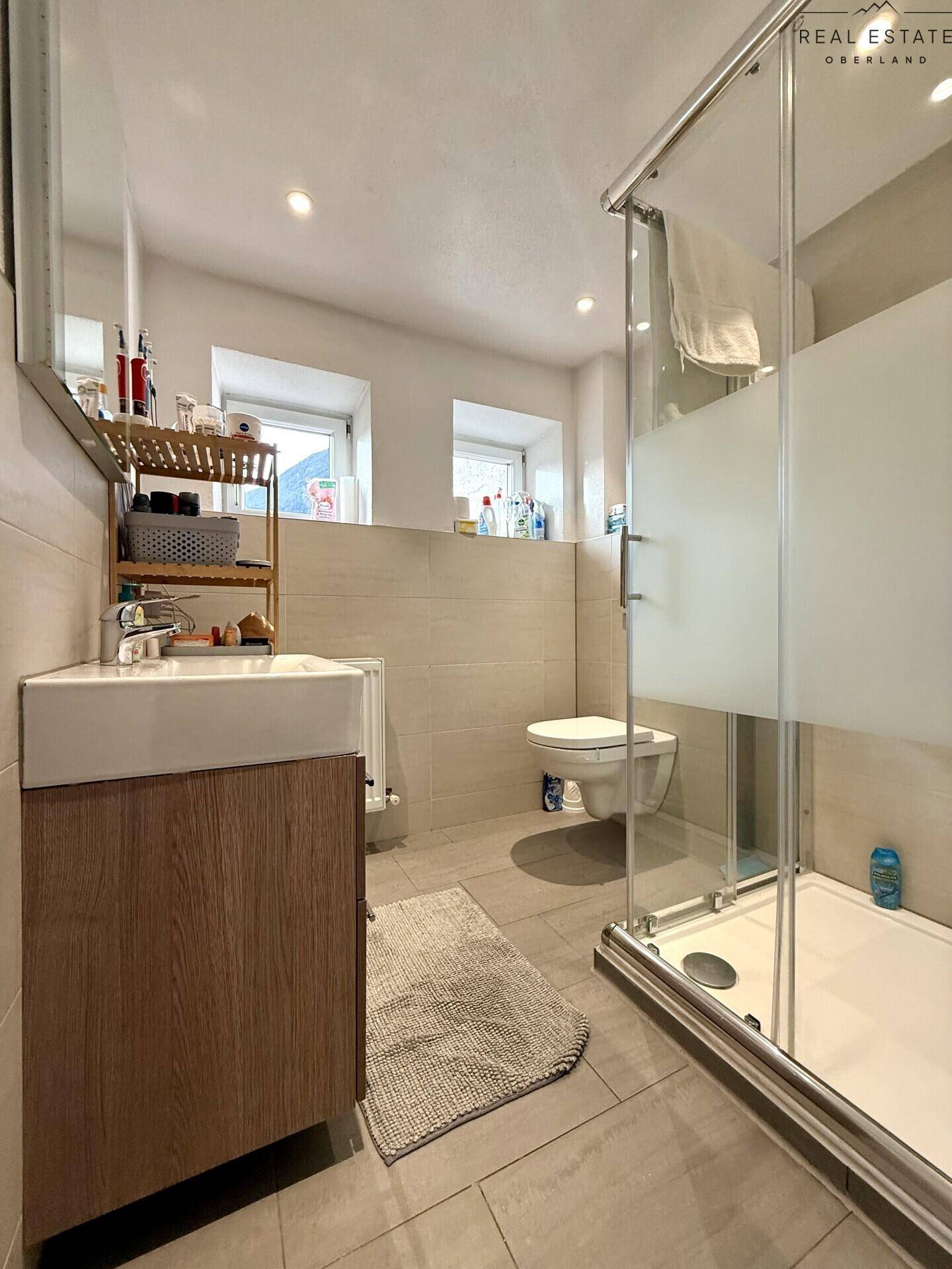 Modernes Badezimmer mit Duschkabine, Waschbecken und Wand-WC.