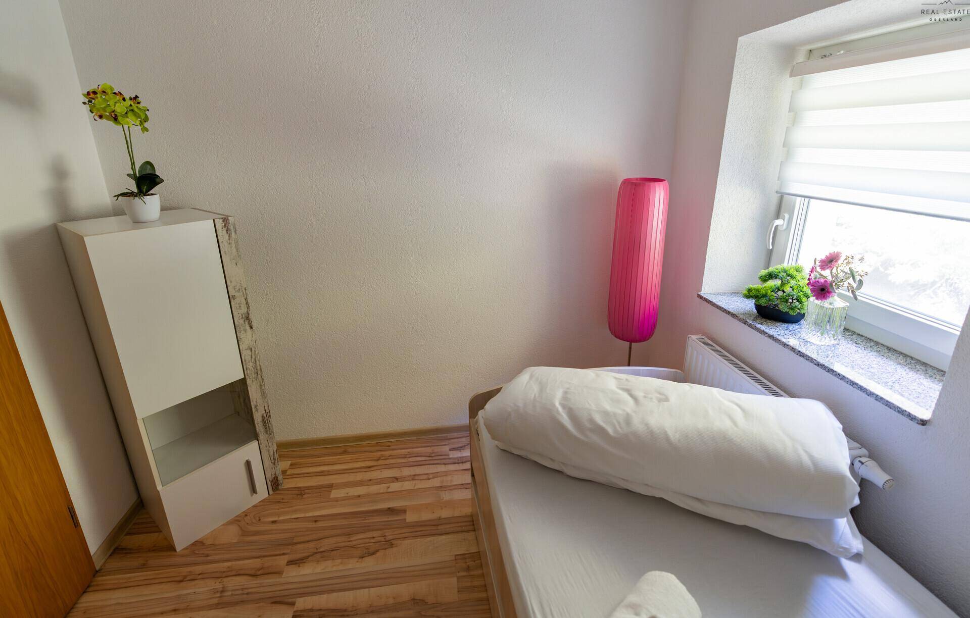 Helles Zimmer mit Einzelbett, Schrank und Fenster für Tageslicht.