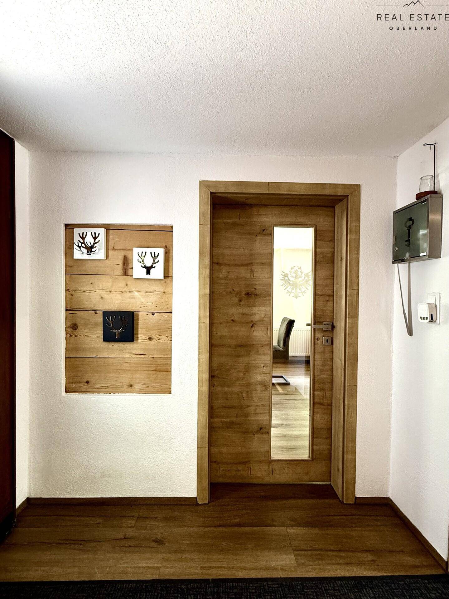Heller Eingangsbereich mit Holztür und dekorativen Wandelementen, einladend gestaltet.