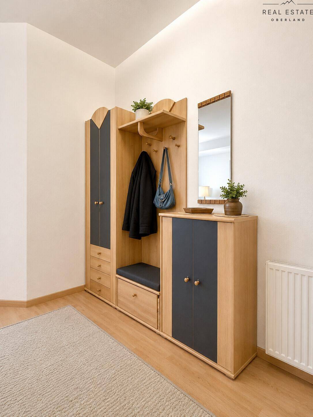 Heller Flur mit moderner Garderobe aus Holz und dunklen Akzenten sowie einem Spiegel.