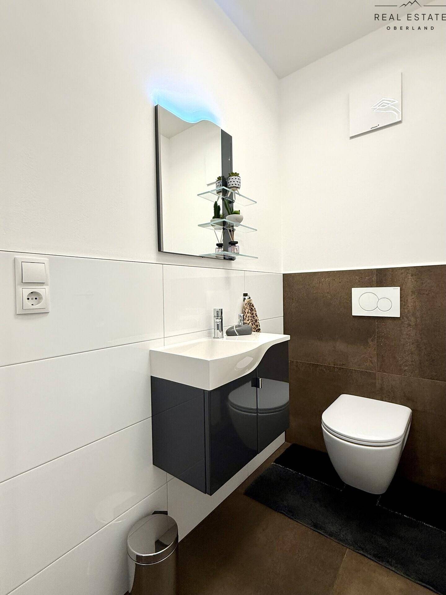 Helles Gäste-WC mit modernem Design, Wand-WC und beleuchtetem Spiegel.