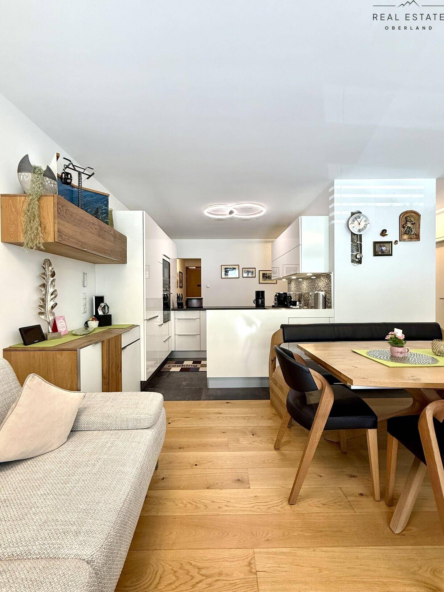 Offener Wohn-Essbereich mit Sofa und Blick auf die moderne, integrierte Küche.