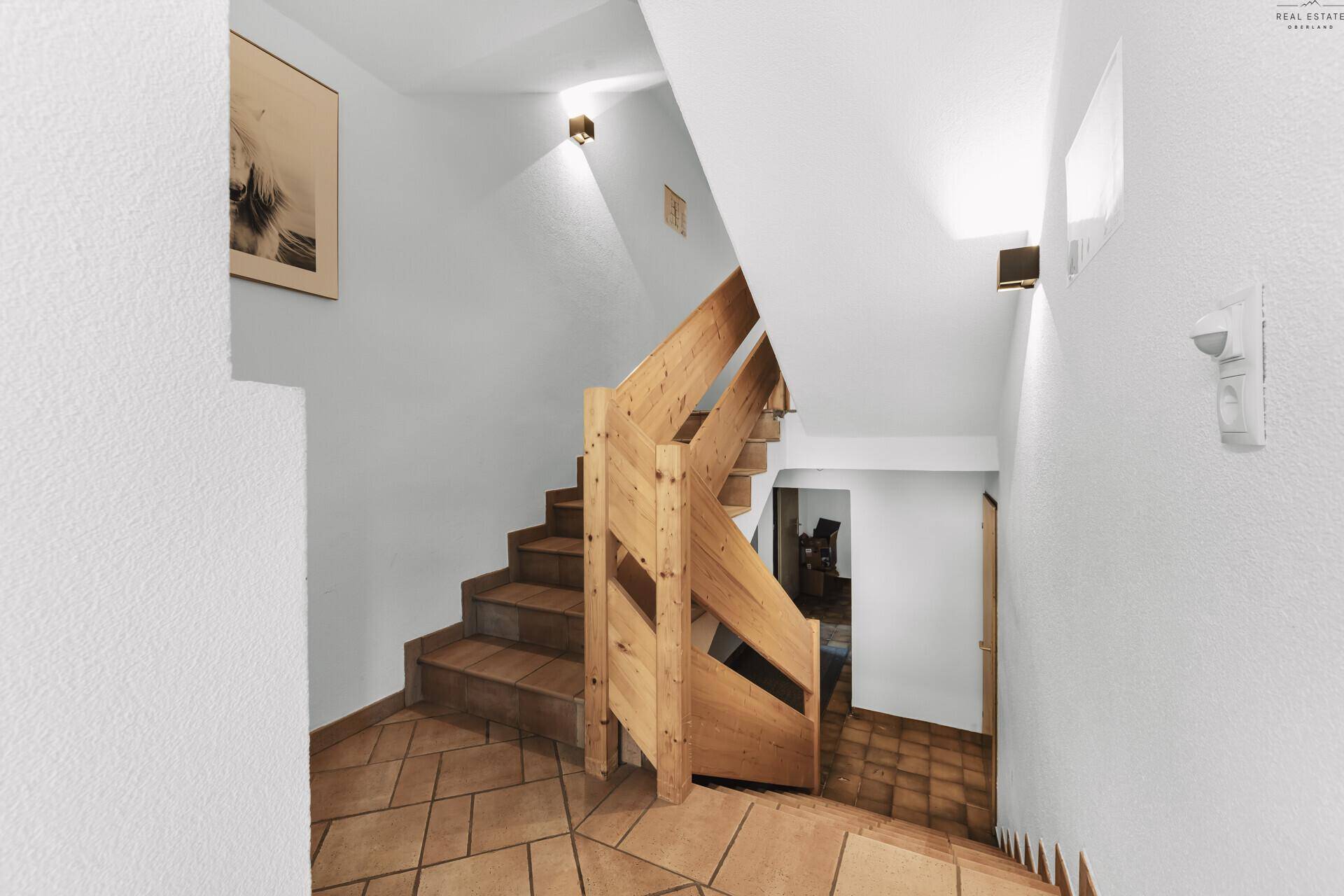 Treppenhaus mit Holzstufen und Fliesenboden, das verschiedene Ebenen des Hauses verbindet.