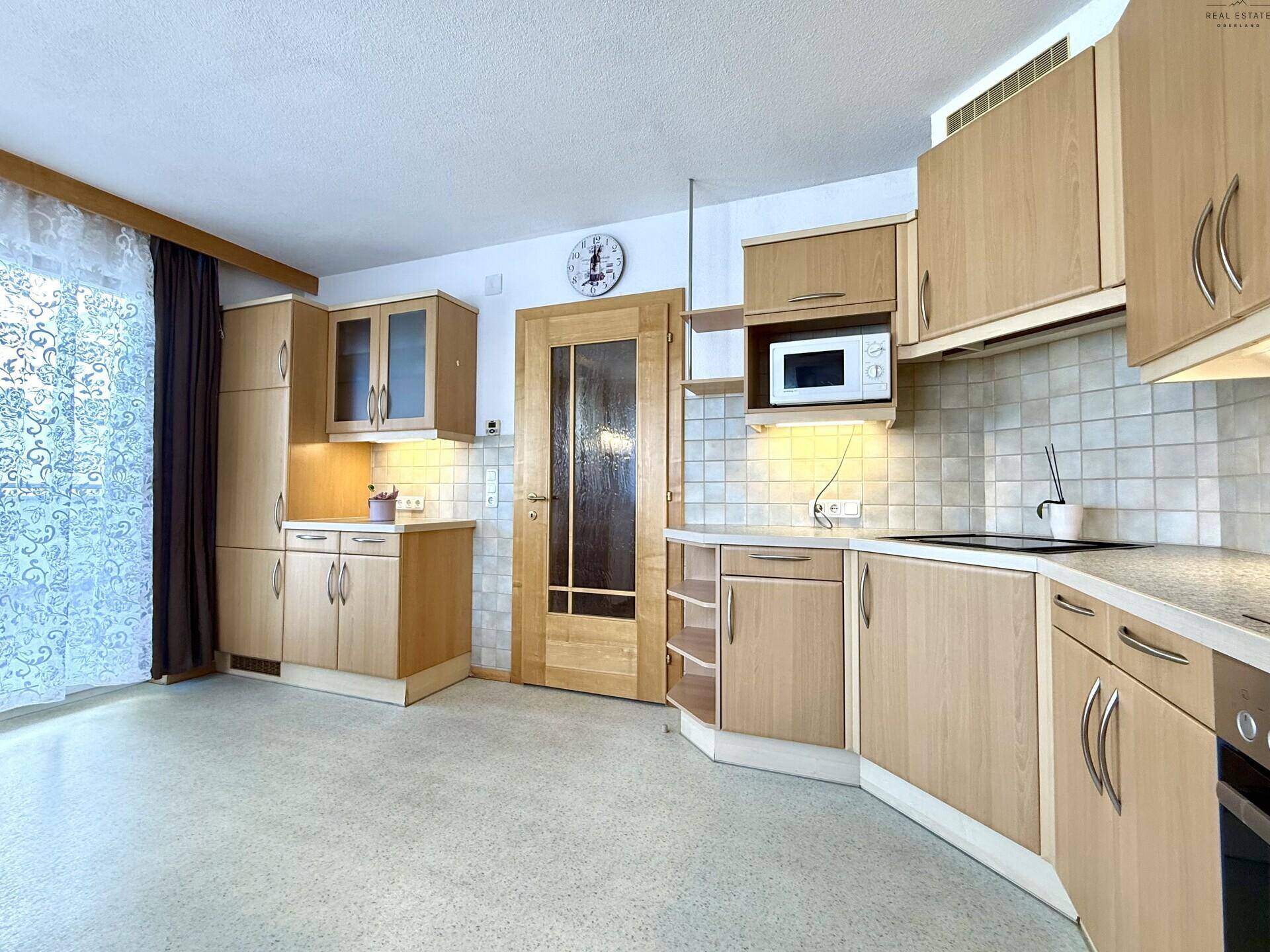 Funktionale Küche mit hellen Holzfronten, integrierten Geräten und großem Fenster.