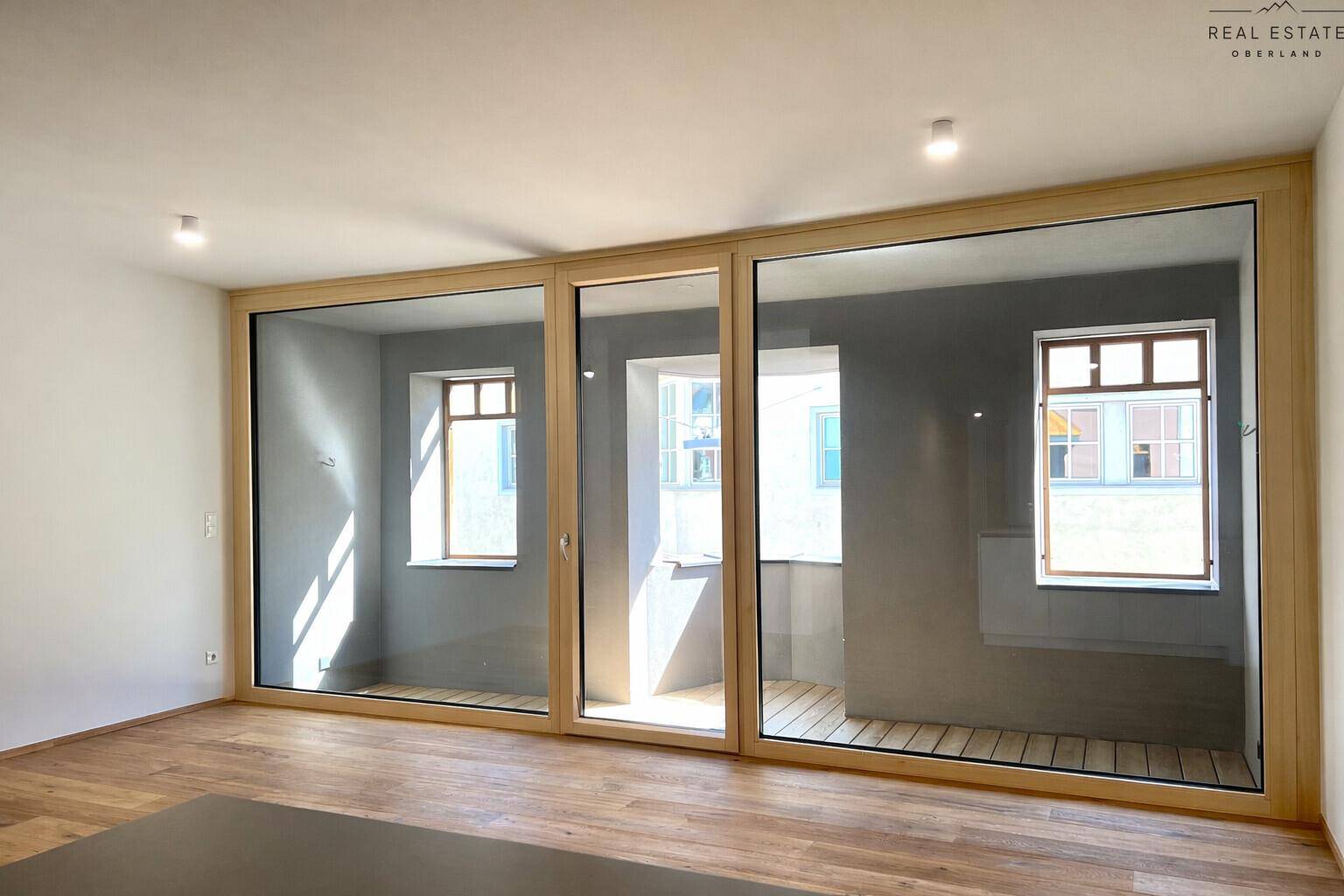 Große, bodentiefe Fenster mit Holzrahmen, die viel Tageslicht in den Wohnbereich lassen.