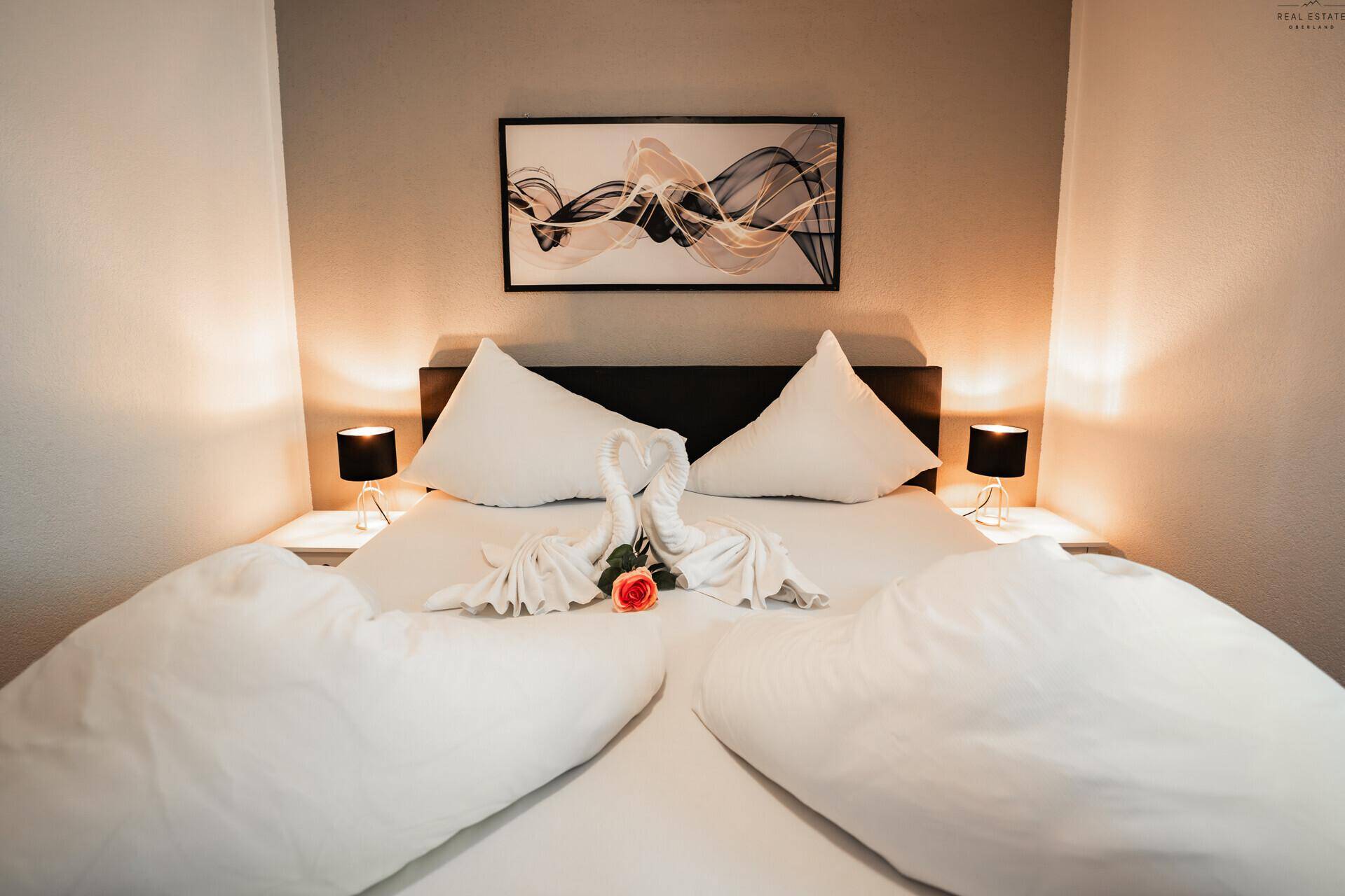 Gemütliches Doppelbett im Schlafzimmer mit dekorativen Handtüchern und Nachttischlampen.