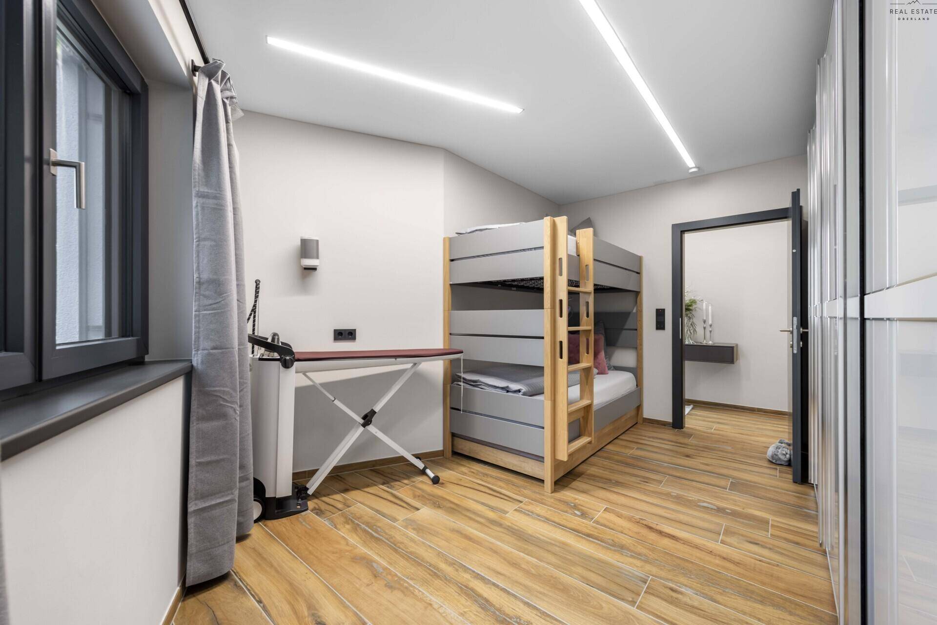 Funktionales Schlafzimmer mit Etagenbett, Bügelbrett und praktischen Einbauschränken.
