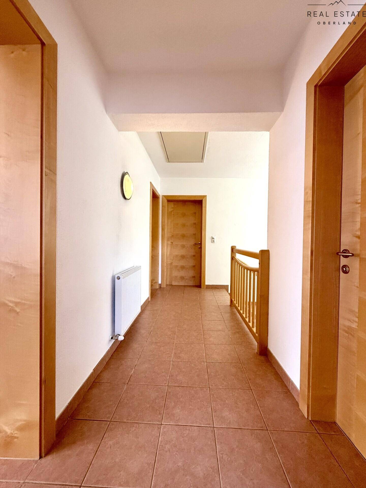 Heller Flur mit Fliesenboden und Holztüren, der zu verschiedenen Räumen im Haus führt.