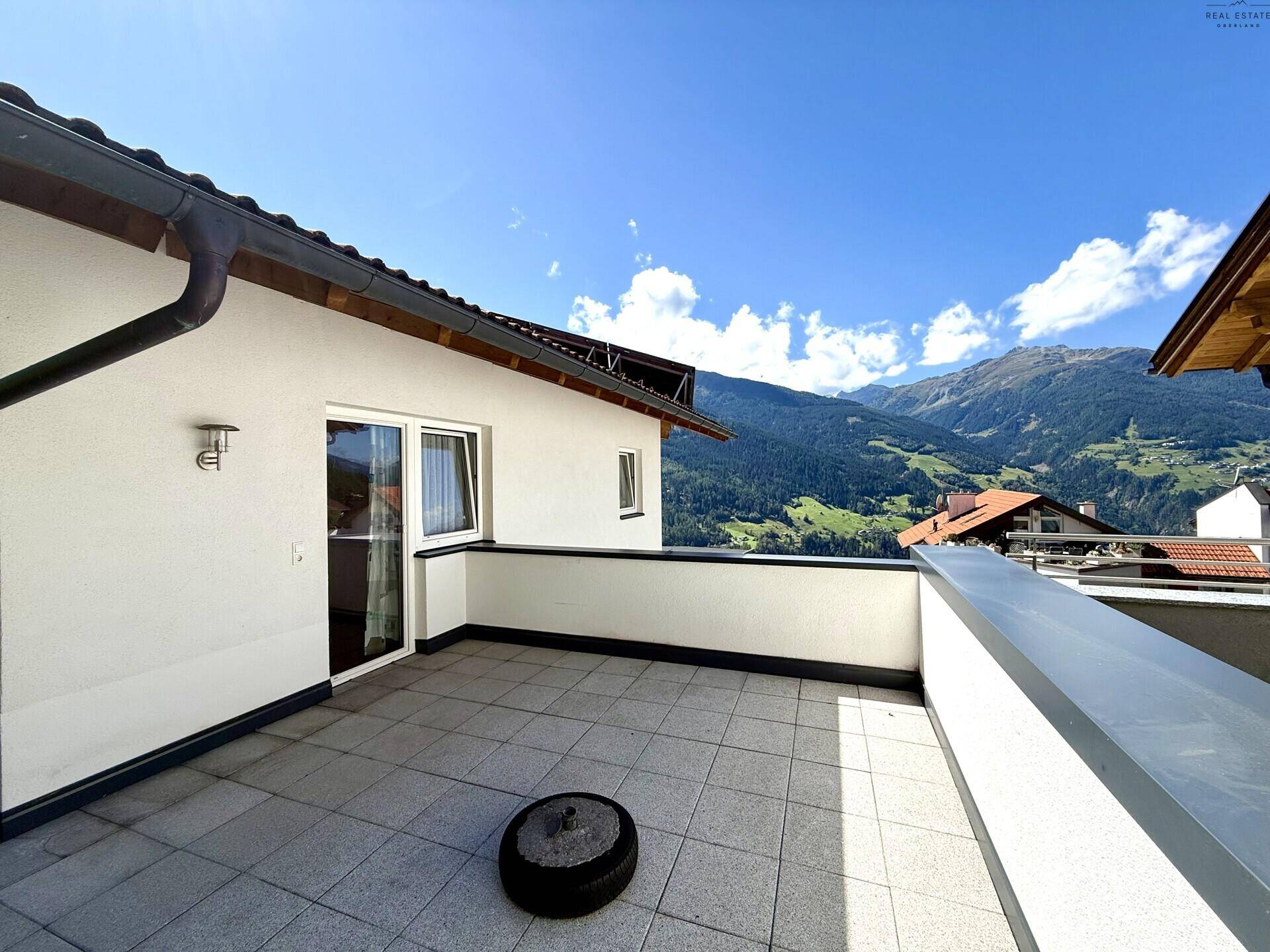 Große geflieste Terrasse mit Bergblick, ideal für Entspannung im Freien und Sonnenbaden.