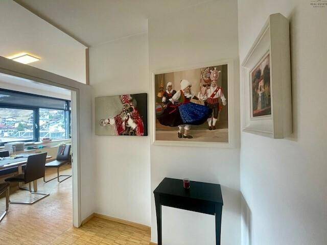Flur mit Kunstwerken an der Wand und Blick in ein angrenzendes Bürozimmer.