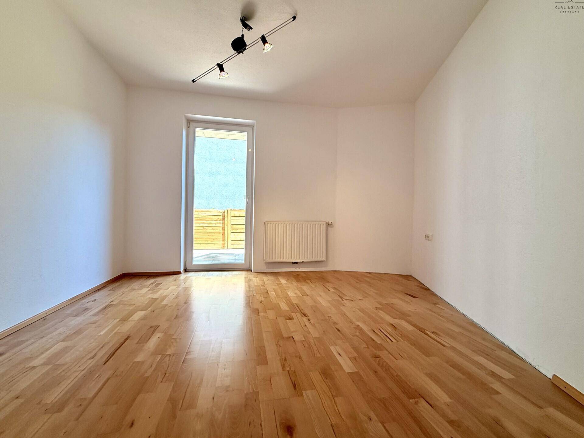 Geräumiges Schlafzimmer mit Holzboden, weißen Wänden und viel Tageslicht.
