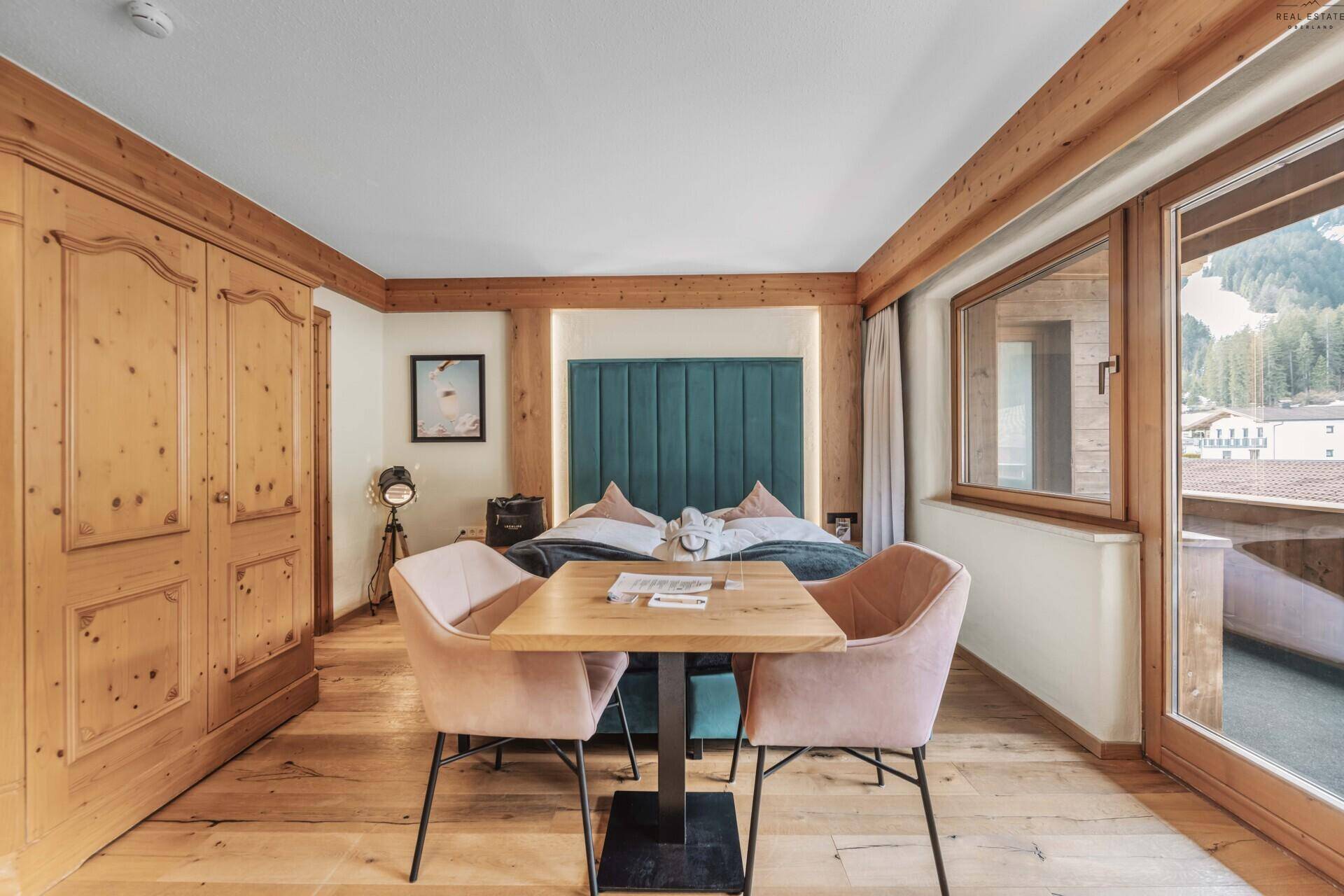Gemütliches Schlafzimmer mit Doppelbett, Holzboden und Zugang zu einem Balkon.