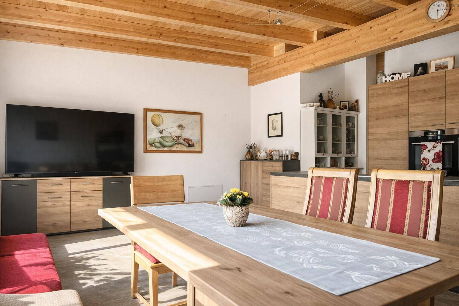 Offener Wohn- und Essbereich mit Holzbalkendecke, großem Esstisch und Fernseher.