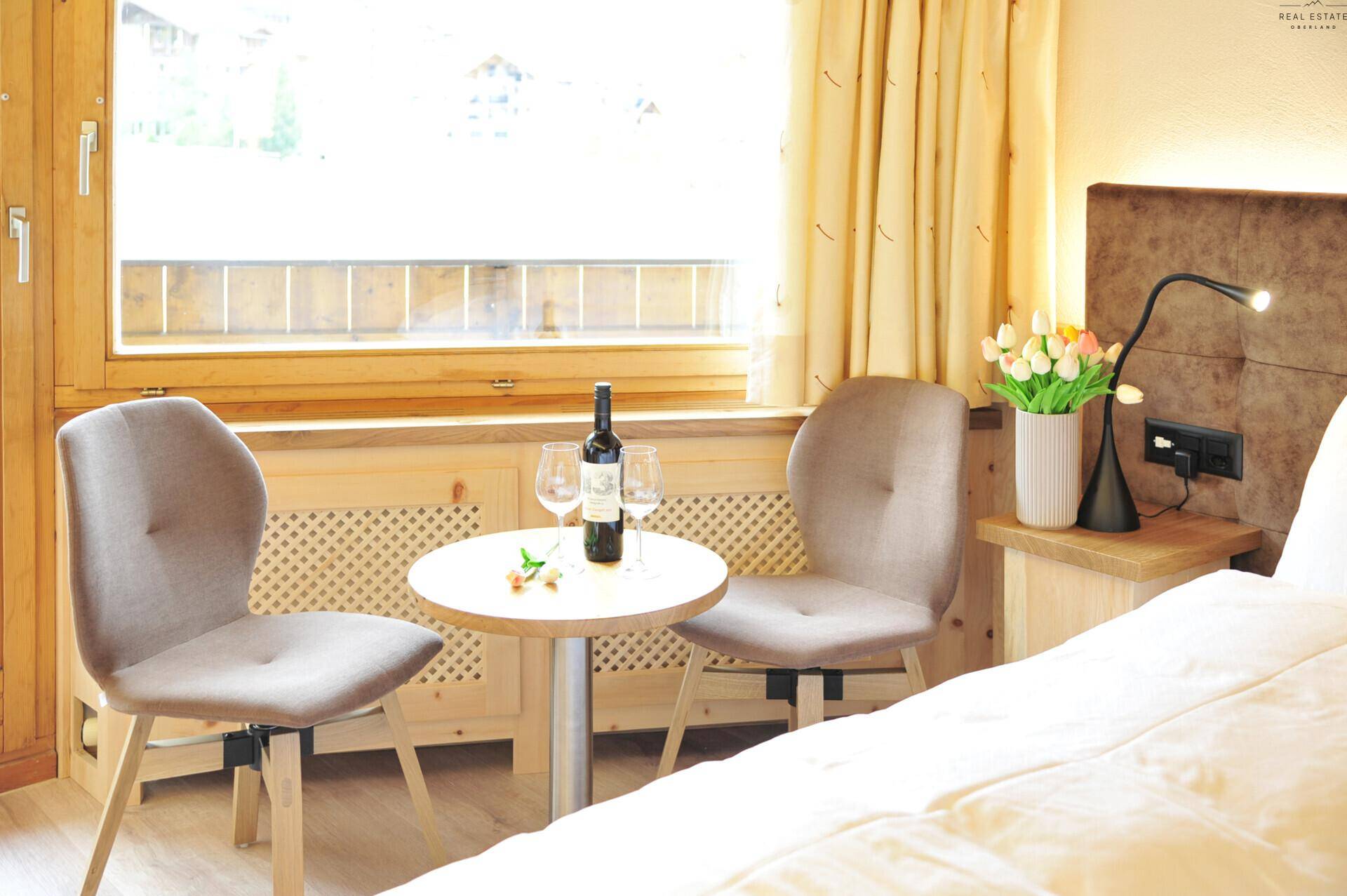 Detailansicht eines kleinen Tisches mit Stühlen im Schlafzimmer, mit Blick durch das Fenster.