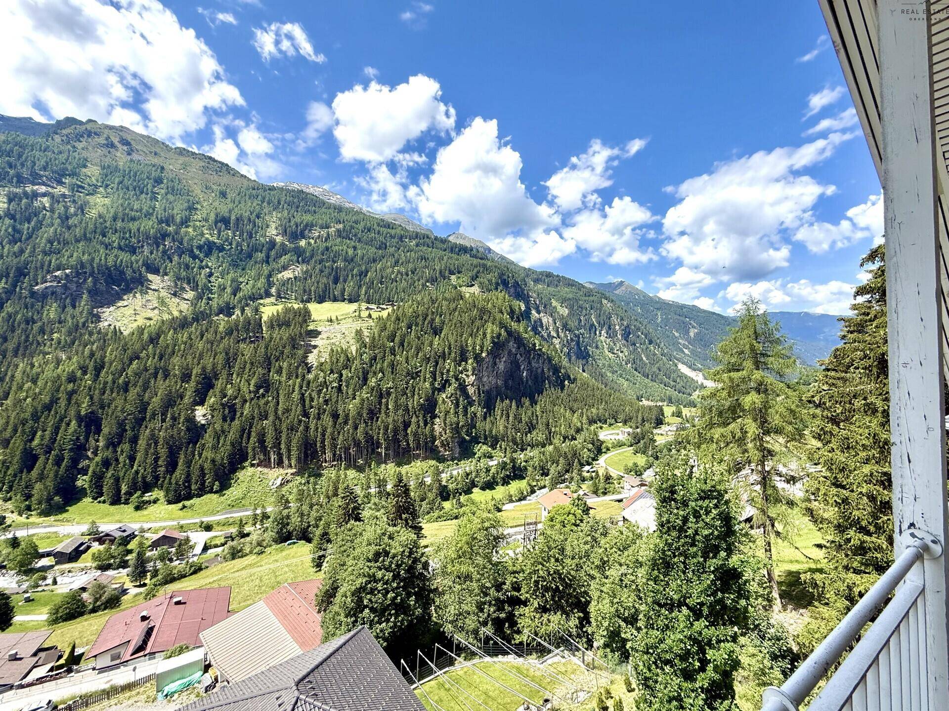 Panoramablick von einem Balkon auf die majestätischen Berge und das grüne Tal.