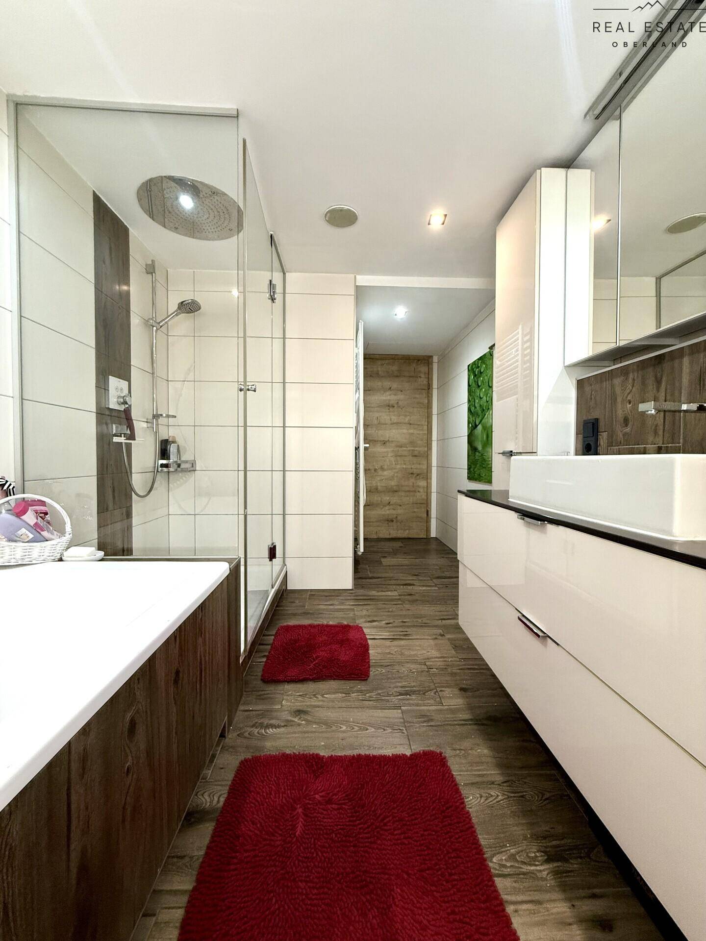 Modernes Badezimmer mit Badewanne, Glasdusche und elegantem Waschbecken, gut beleuchtet.