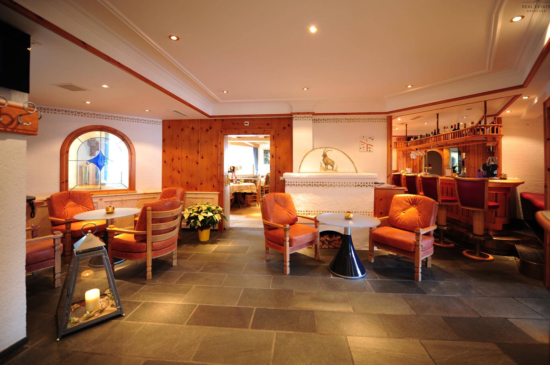 Gemütlicher Loungebereich mit traditioneller Holzvertäfelung, Steinfliesenboden und einer Bar im Hintergrund.