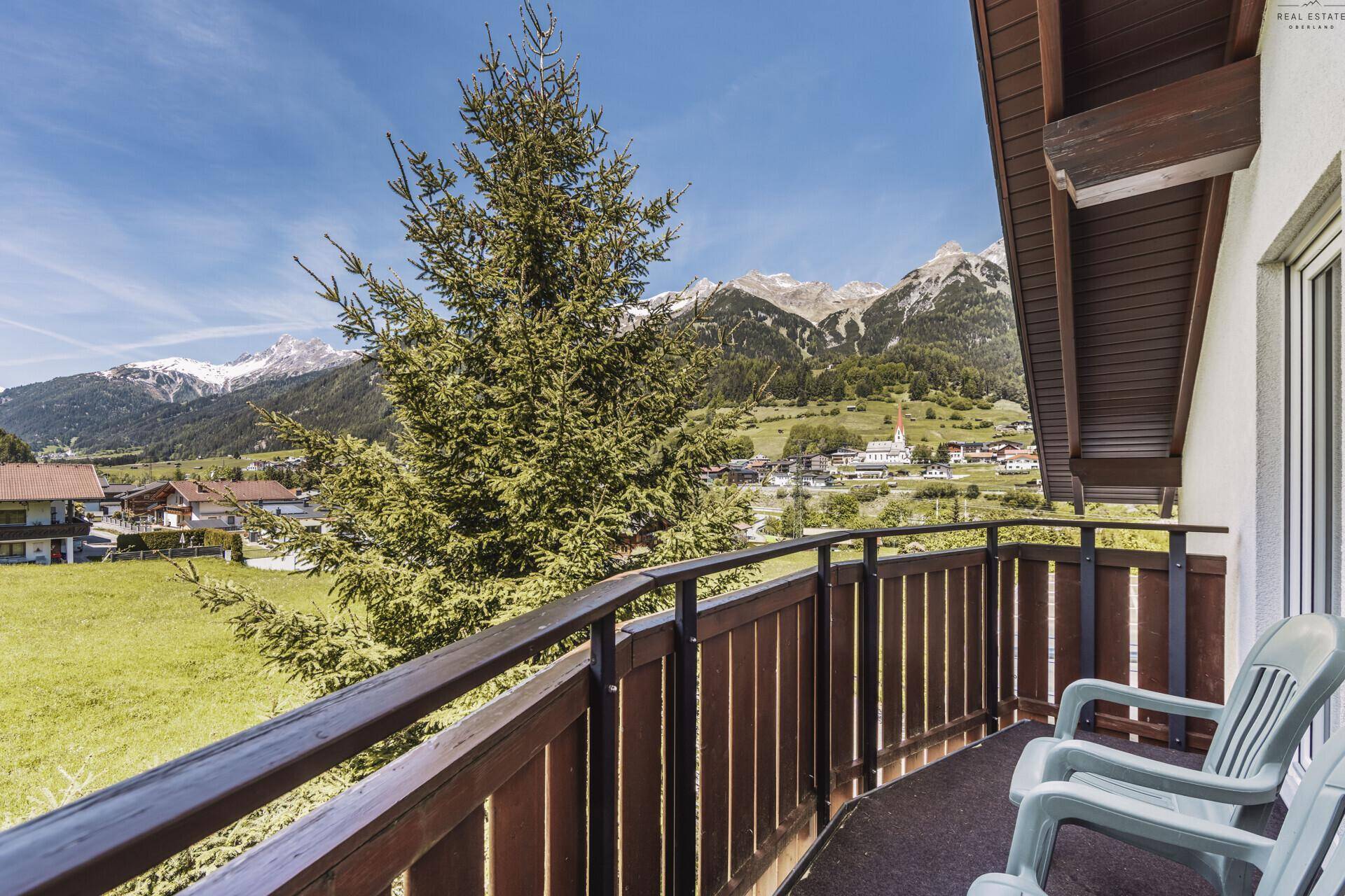 Balkon mit Holzgeländer und atemberaubendem Panoramablick auf die umliegende Bergwelt.