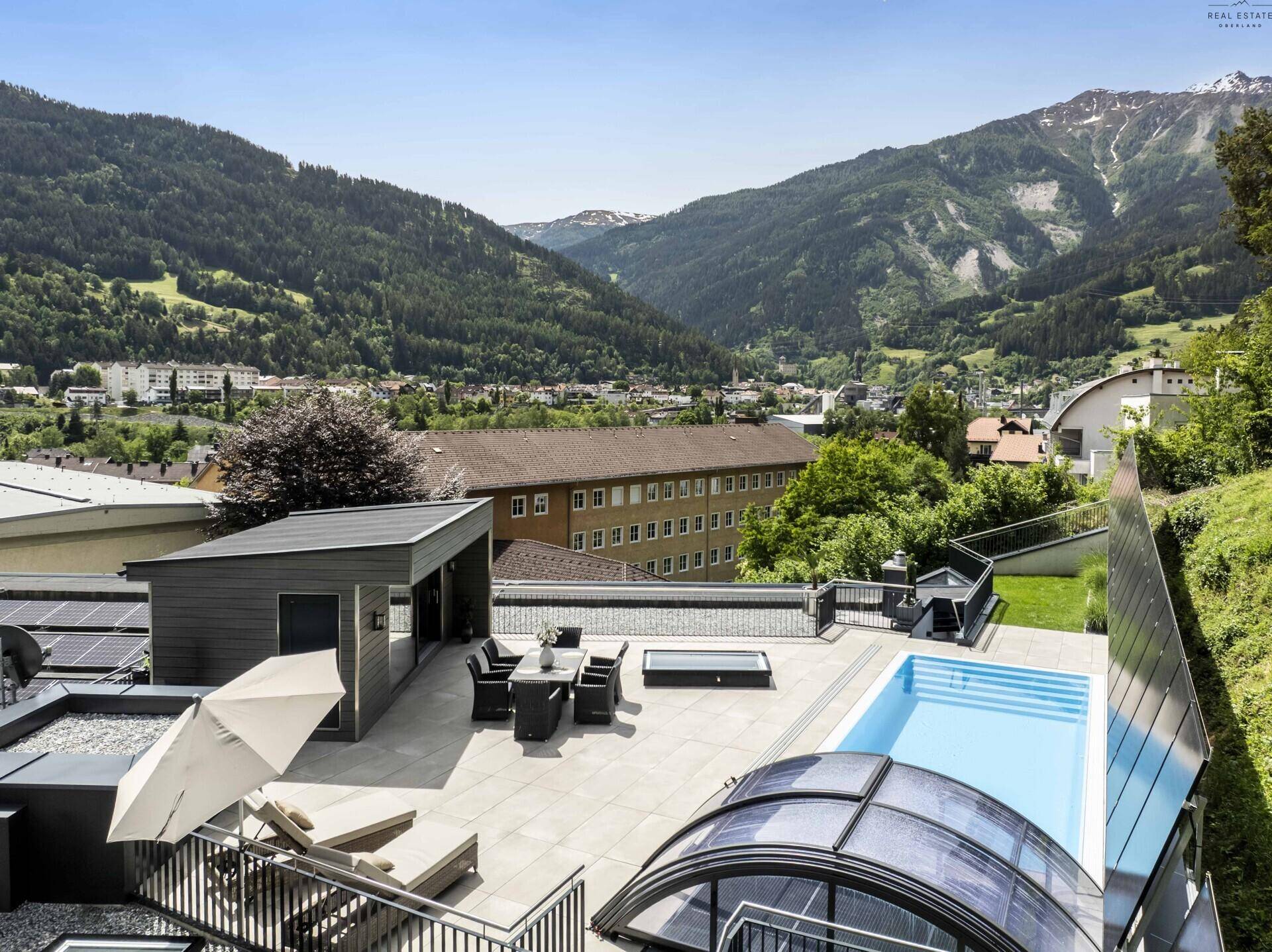 Panoramablick auf die weitläufige Terrasse mit Pool und Essbereich, eingebettet in eine Berglandschaft.