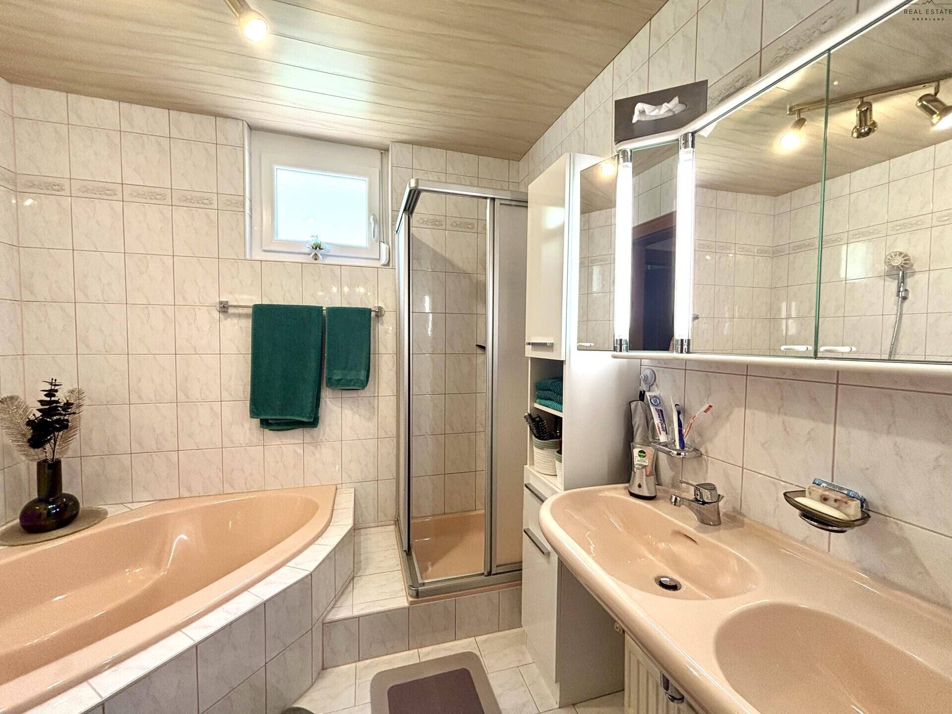 Geräumiges Badezimmer mit Eckbadewanne, Duschkabine und Einzelwaschbecken, hell gefliest.