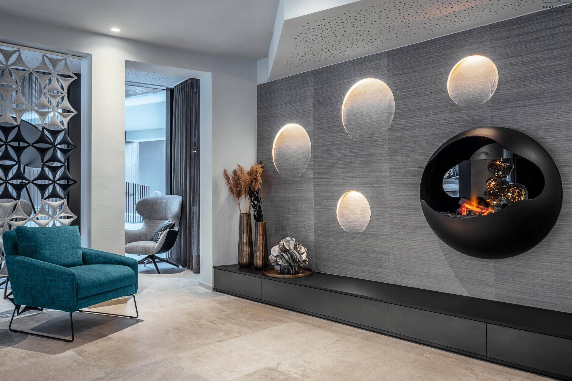 Stilvolle Lounge mit modernem Kamin, dekorativen Wandleuchten und bequemen Sitzgelegenheiten.