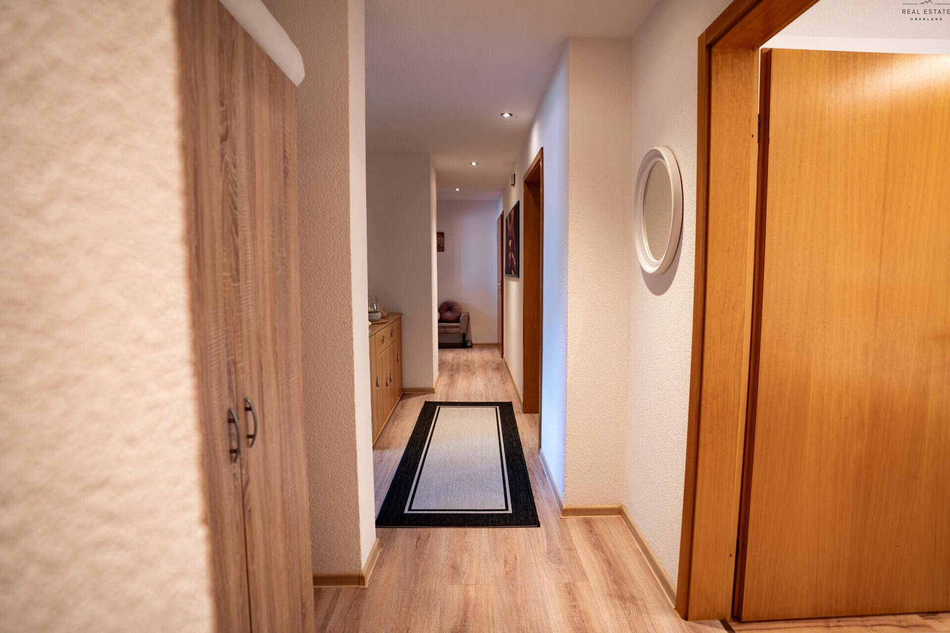 Heller Flur mit Holzoptikboden und Einbauschrank, der zu weiteren Räumen führt.