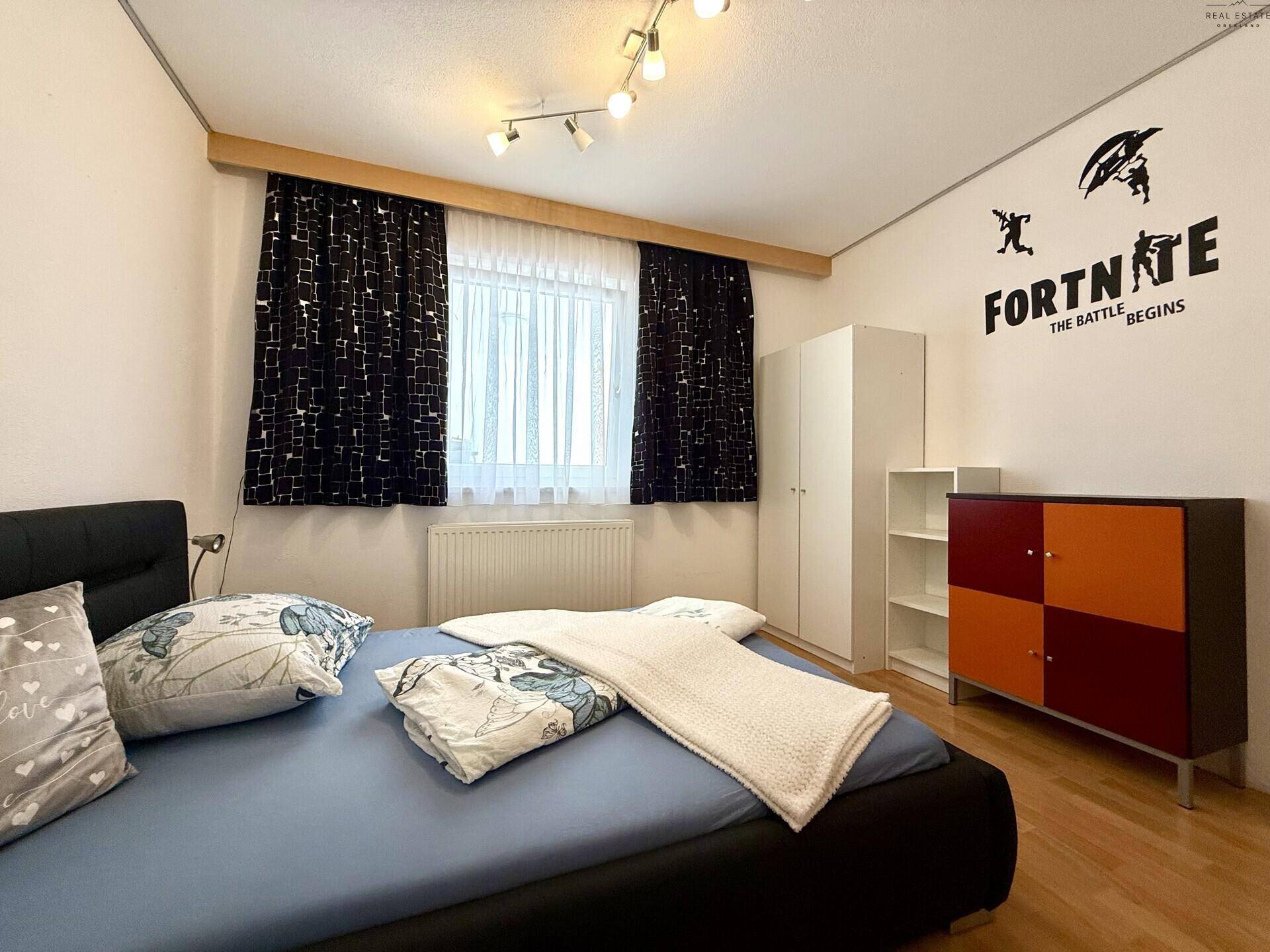 Kinderzimmer mit Bett, Schrank und Wanddekoration im Gaming-Stil.