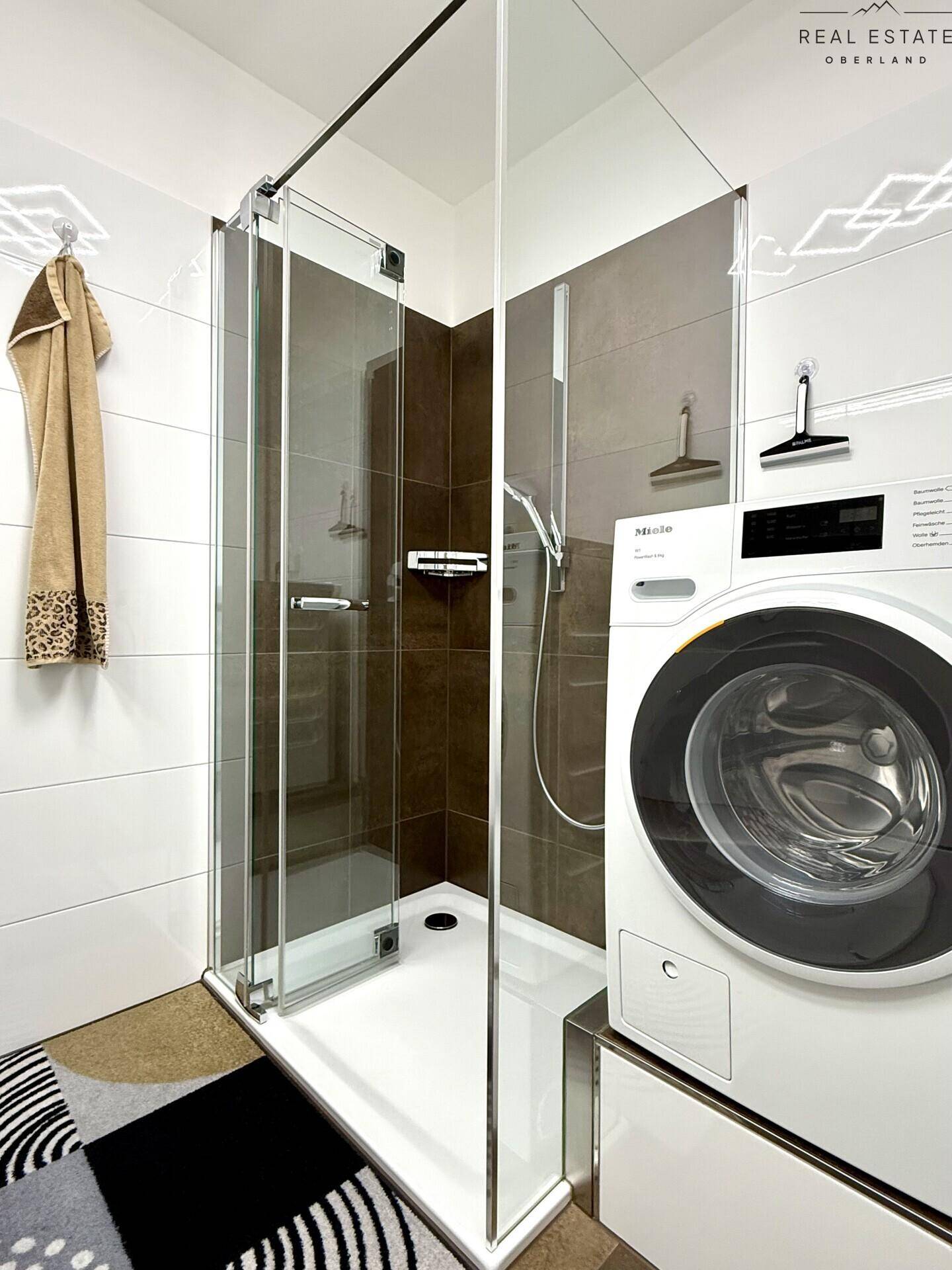 Detaillierte Ansicht der modernen Duschkabine im Badezimmer mit Waschmaschine.