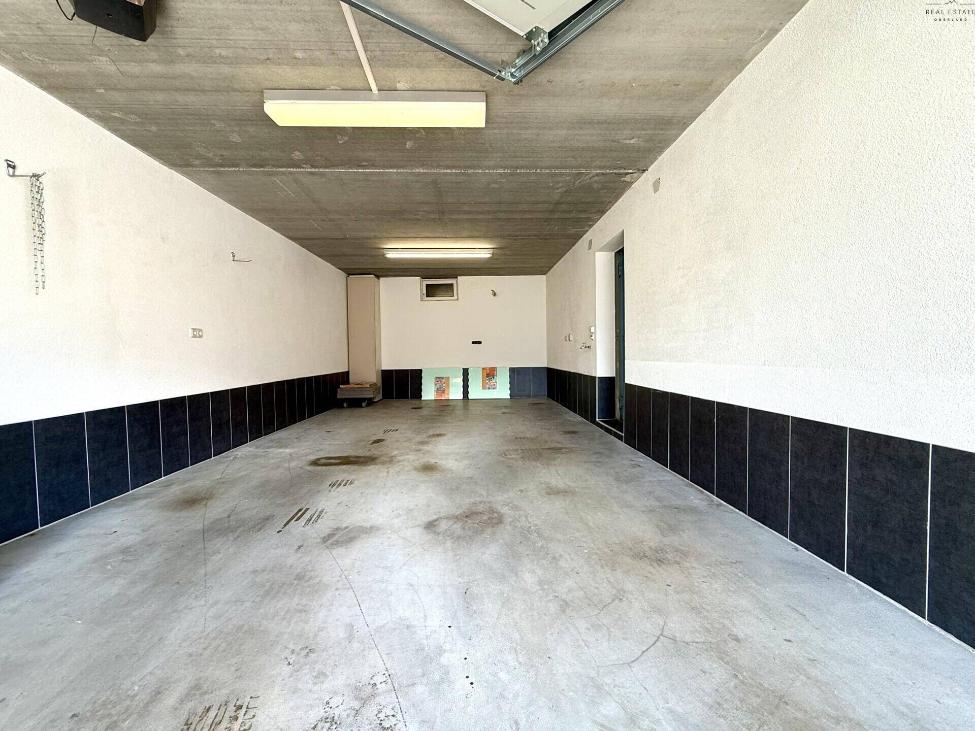 Geräumige Garage mit Betonboden und ausreichend Platz für Fahrzeuge und Lagerung.