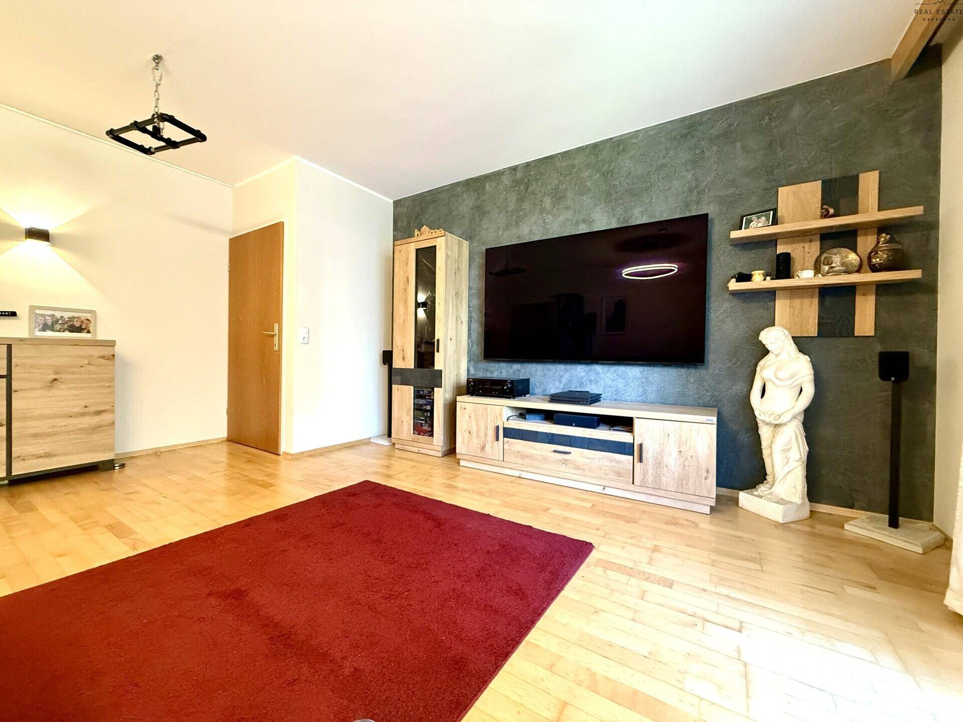 Modernes Wohnzimmer mit Holzboden, großem Fernseher und stilvoller Dekoration.