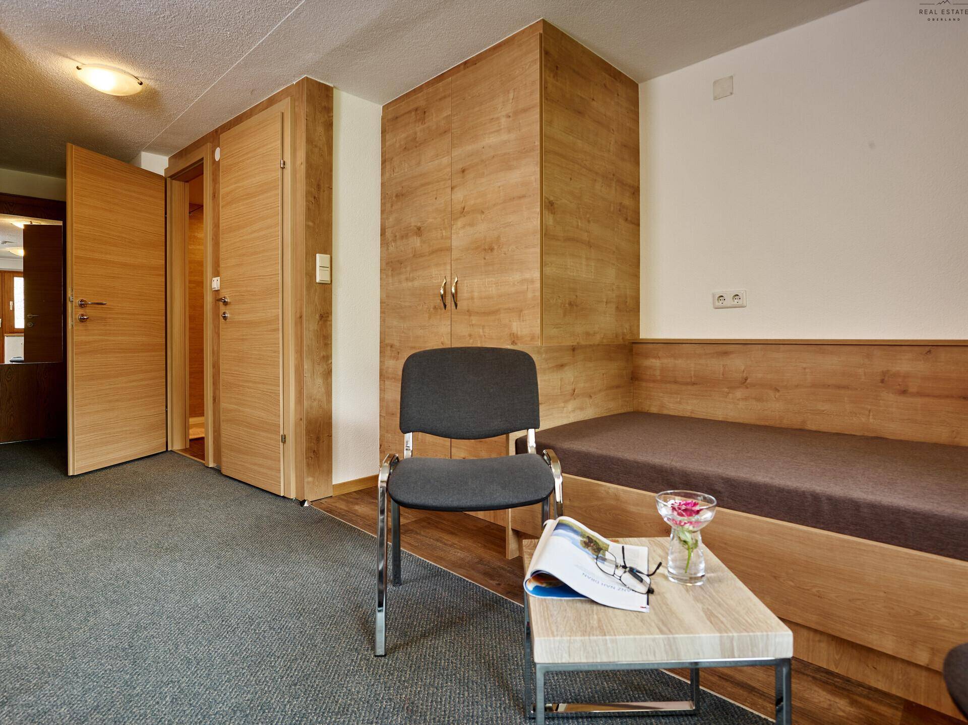 Schlafzimmer mit Holzeinbauschränken, Tagesbett und einem kleinen Tisch mit Dekoration.
