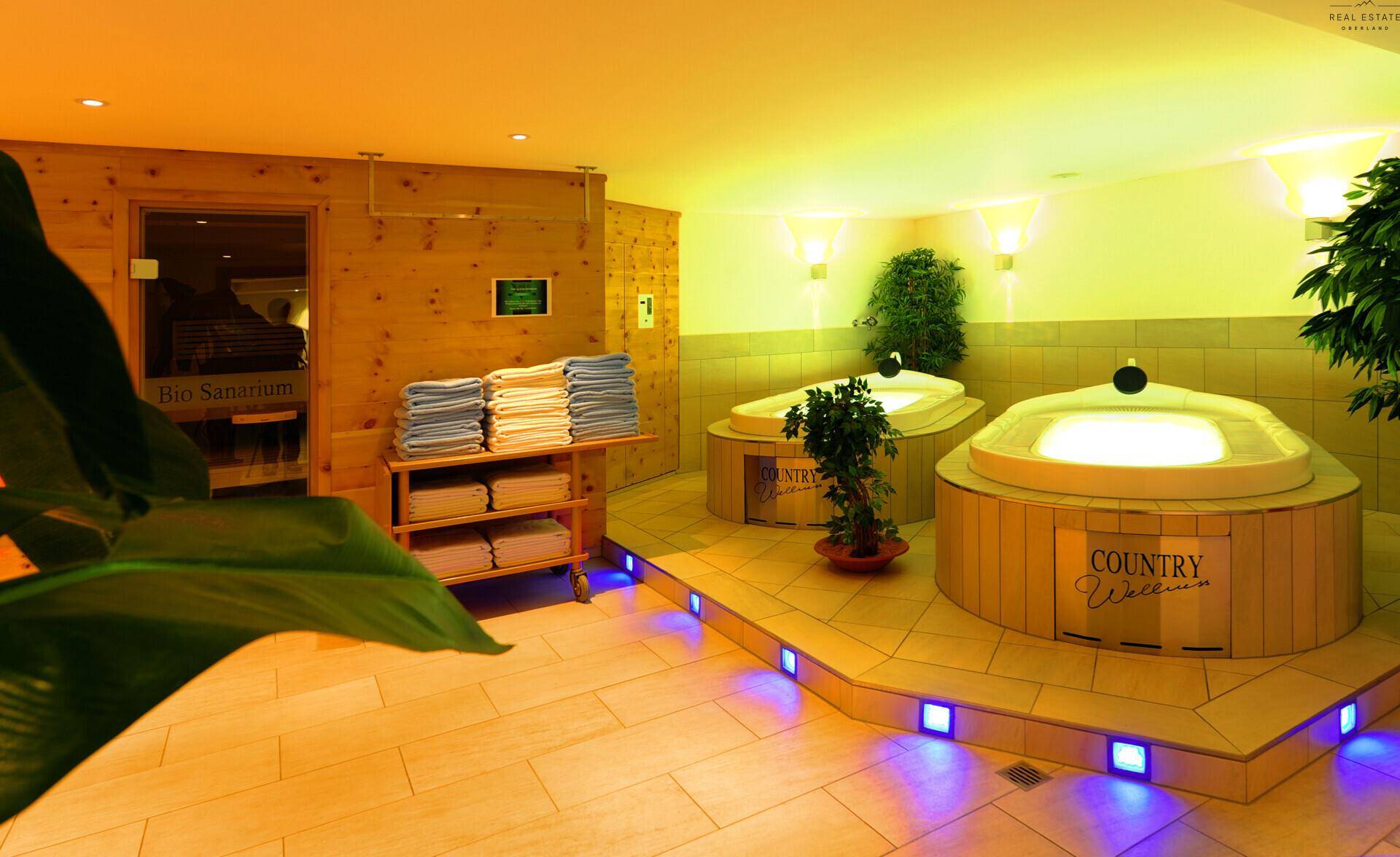 Detailansicht des Wellnessbereichs mit zwei beleuchteten Whirlpools und dem Eingang zu einer Bio-Sauna.