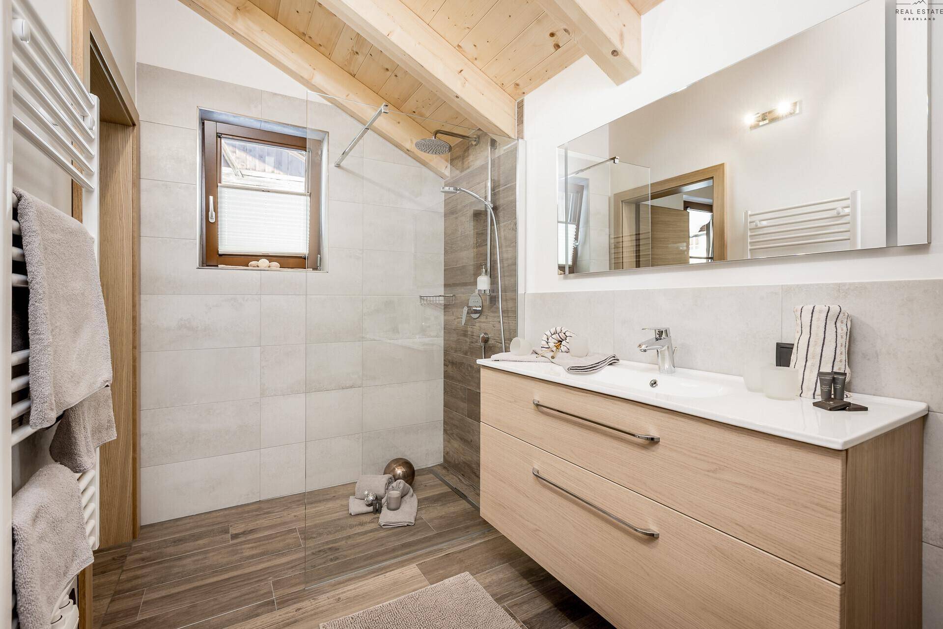 Helles Badezimmer mit großer Dusche, Waschtisch und Fenster für Tageslicht.