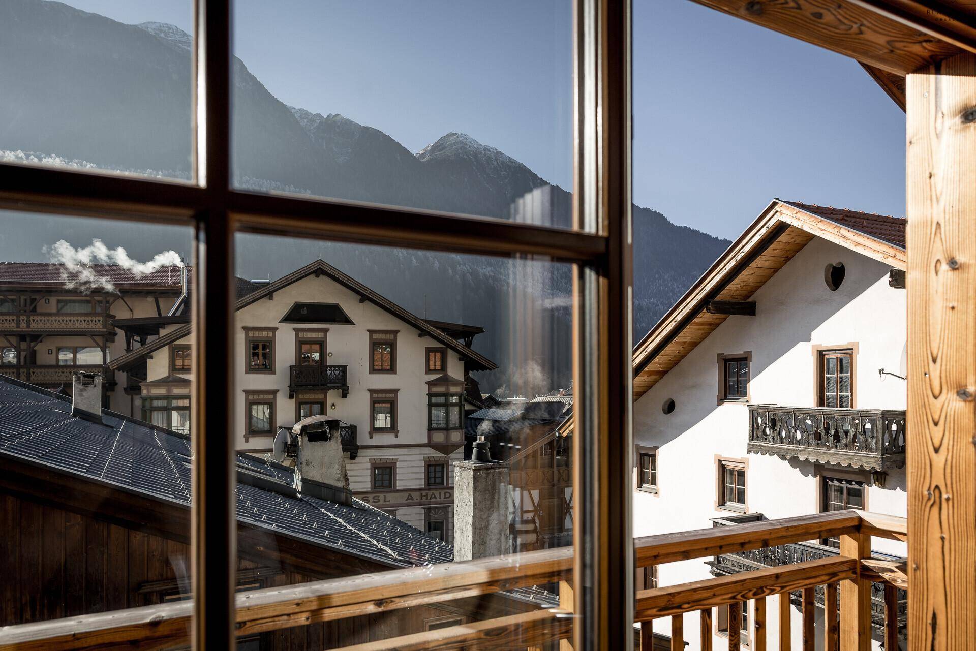 Malerischer Ausblick aus dem Fenster auf traditionelle Häuser und die Bergwelt.