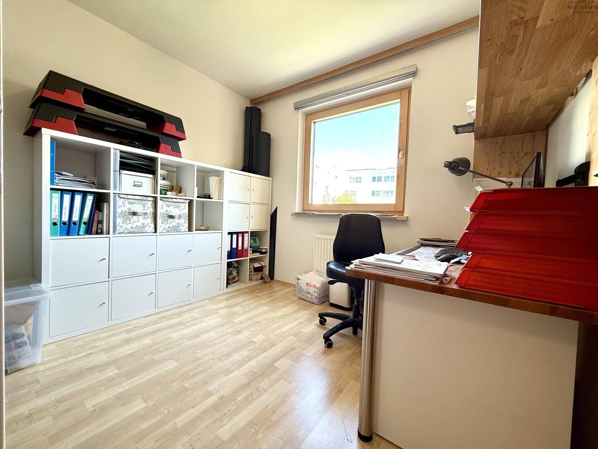 Funktionales Arbeitszimmer mit viel Stauraum, Schreibtisch und Blick ins Grüne.