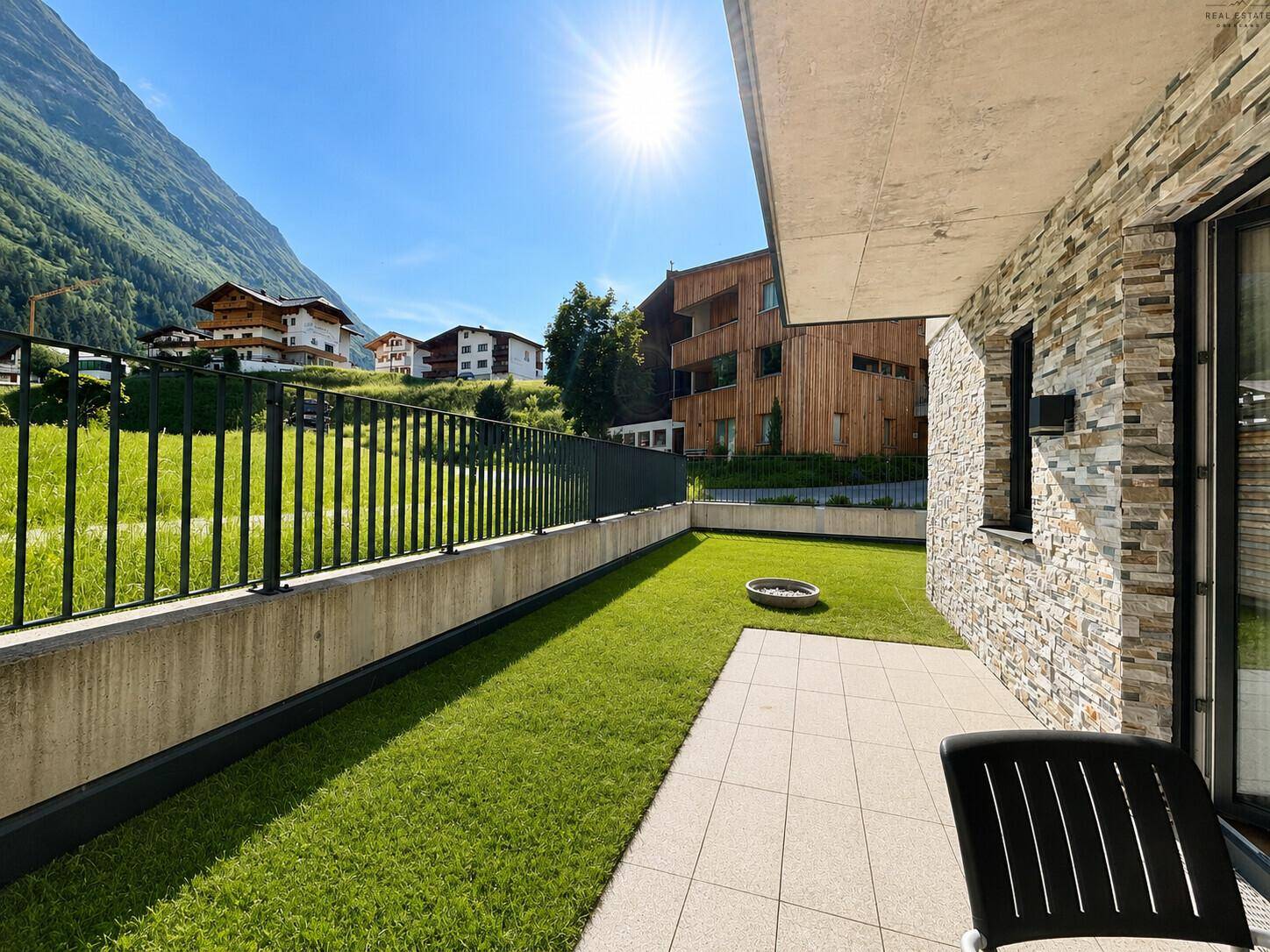 Sonniger Terrassenbereich mit Rasenfläche und Blick auf die umliegende Berglandschaft.