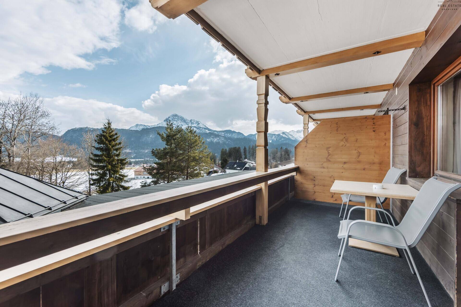 Geräumiger Balkon mit Sitzgelegenheiten und malerischem Blick auf die verschneiten Berge.