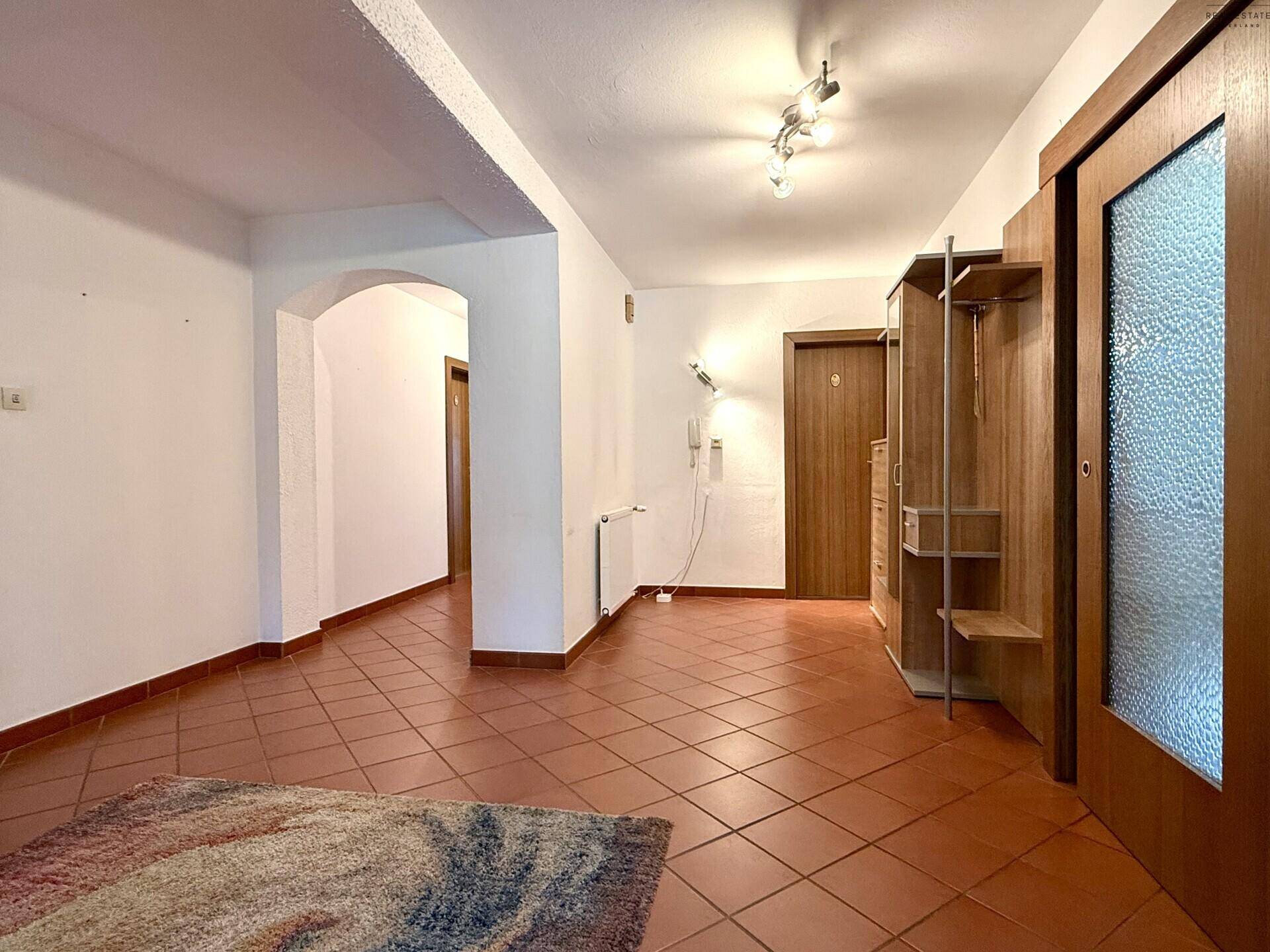 Geräumiger Flur mit Terrakotta-Fliesenboden, Garderobe und Zugang zu verschiedenen Räumen.