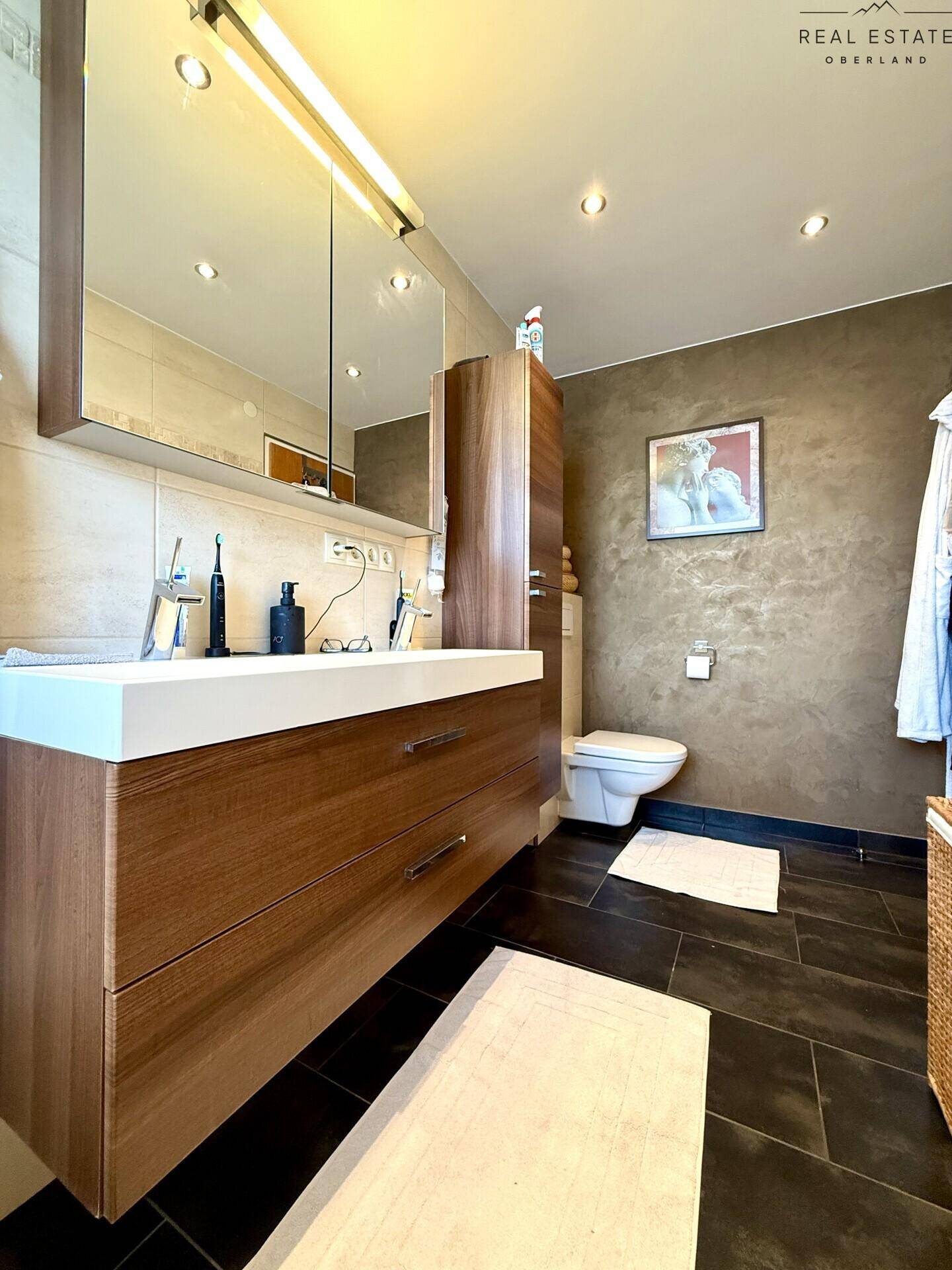 Modernes Badezimmer mit großem Waschbecken, Spiegel und Toilette.