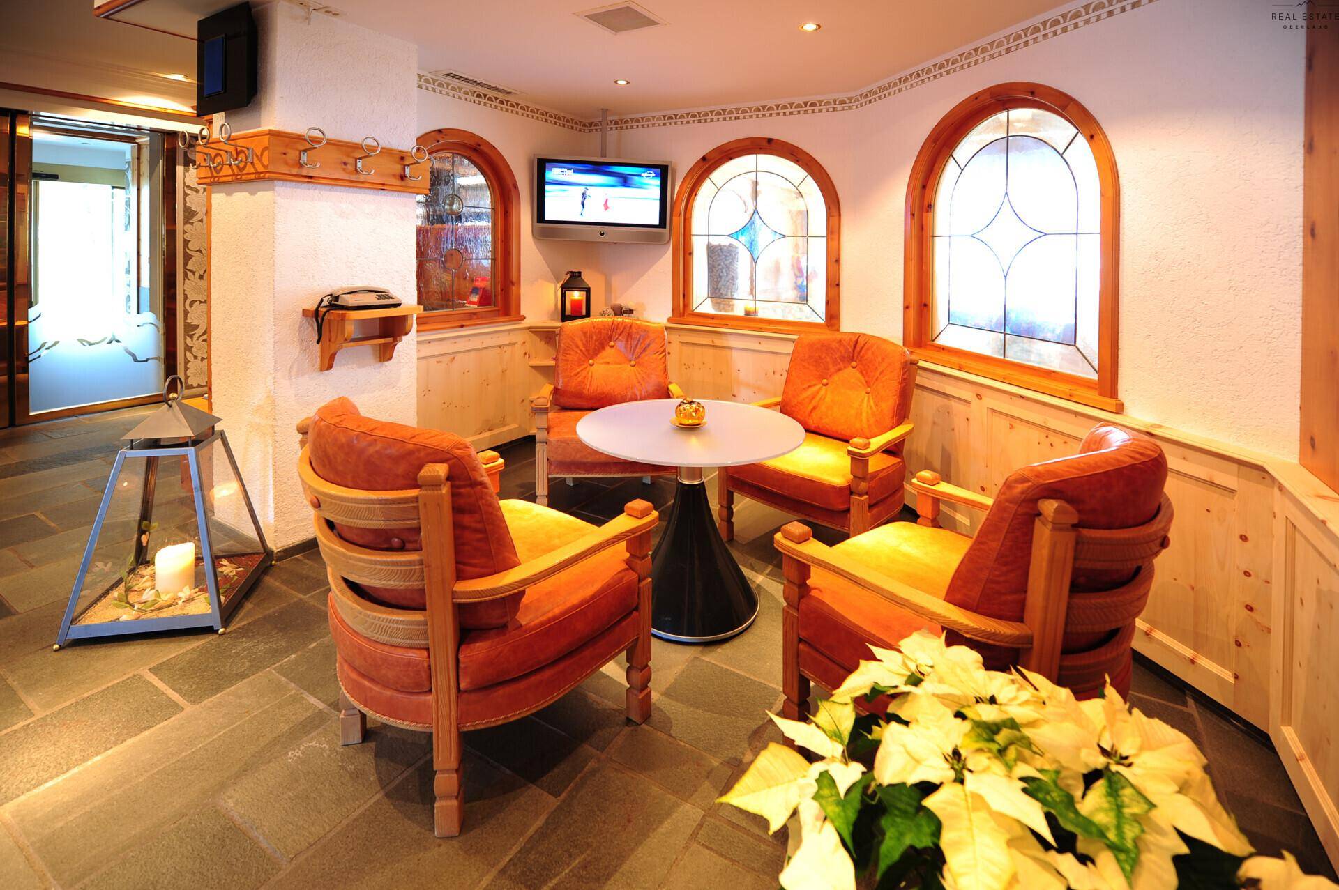 Kleiner Sitzbereich in der Lounge mit vier Sesseln, einem runden Tisch und charmanten Bogenfenstern.